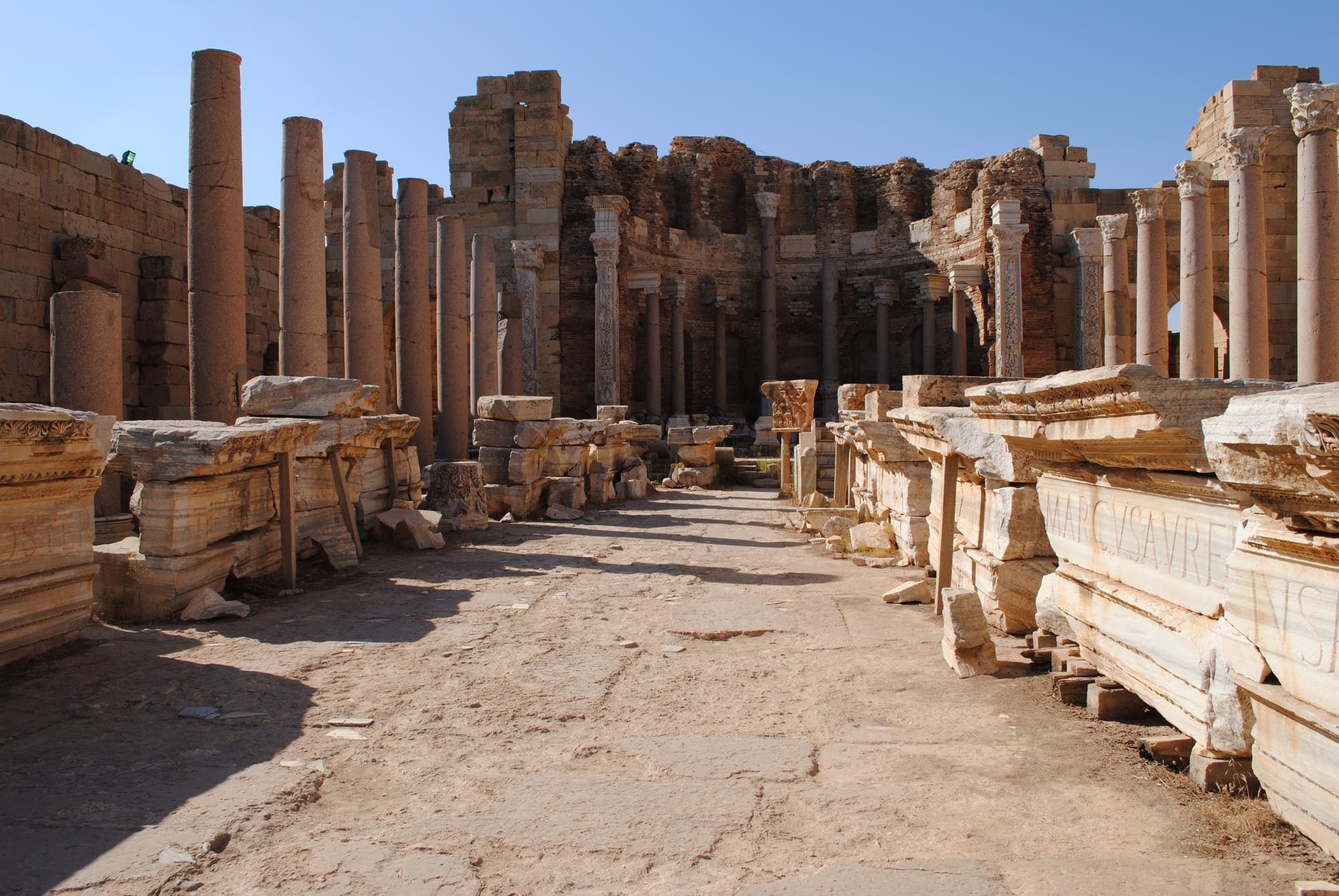 Rows of Roman marble columns and a triumphal arch standing in a coastal ruin field
