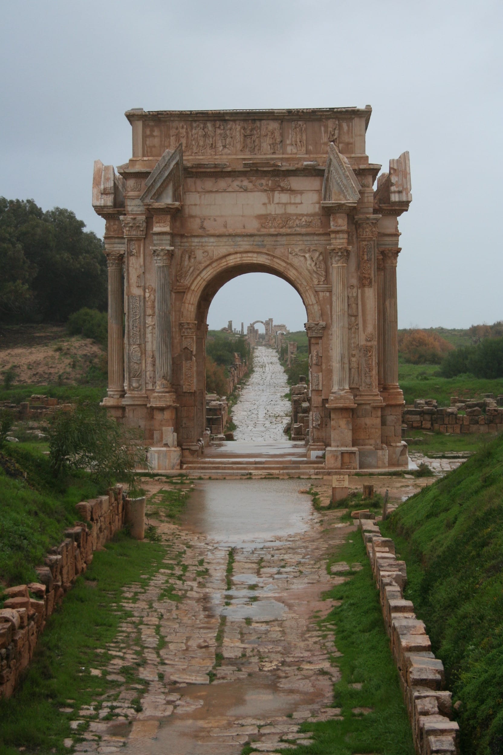 A grand ruined marble archway and colonnaded street
