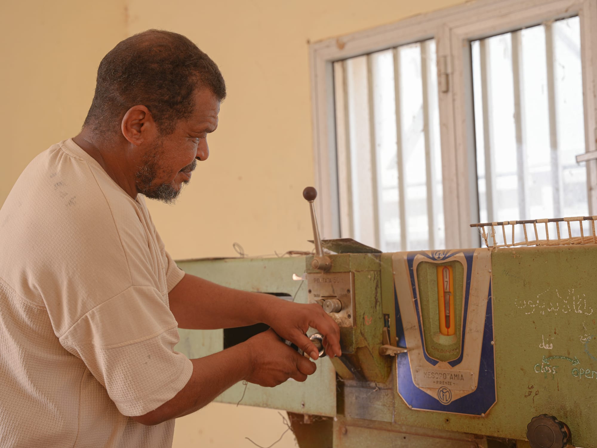A man operating an old mechanical weighing and grading machine used in grain processing