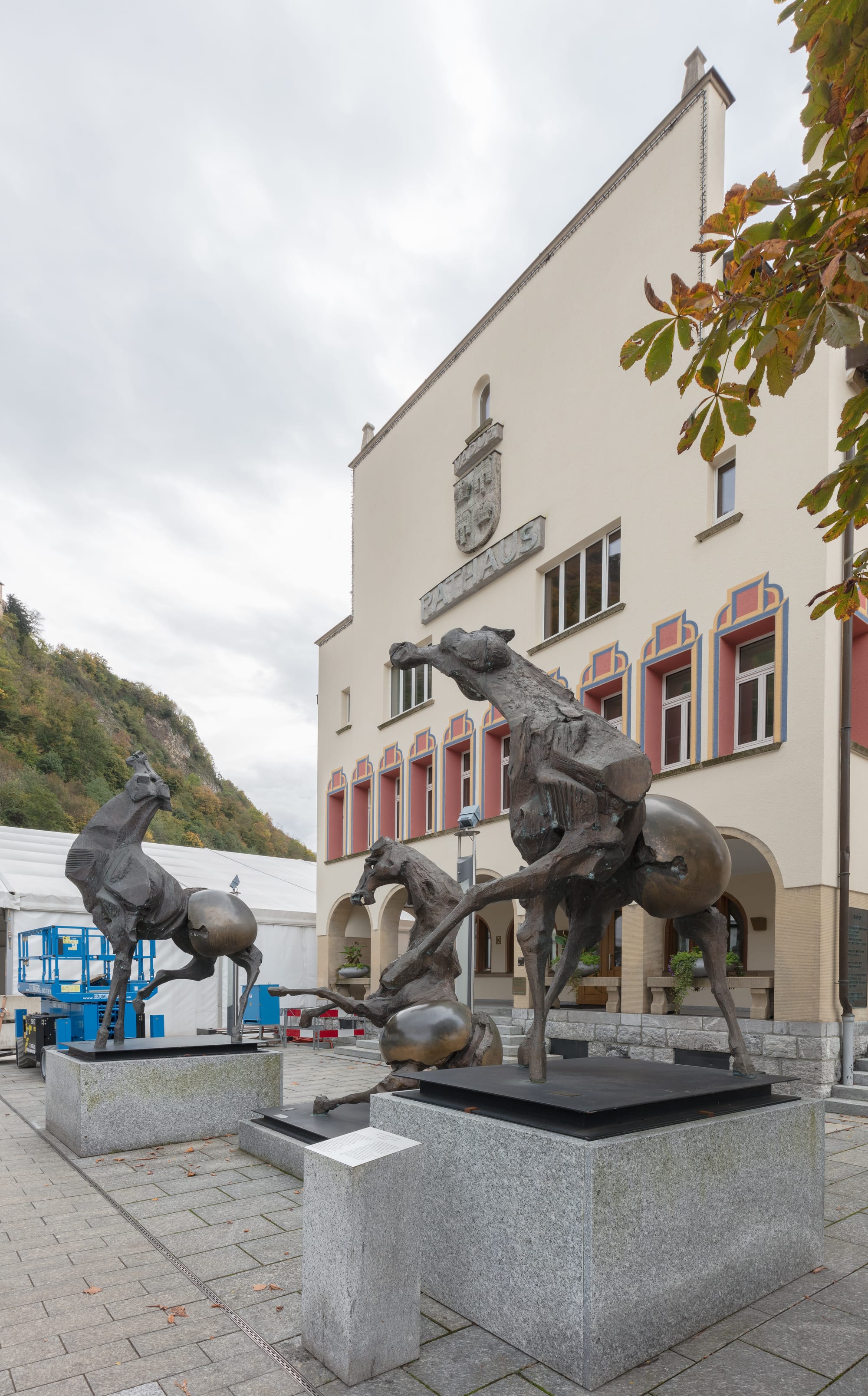 A modern town hall building beside a plaza with a bronze horse sculpture