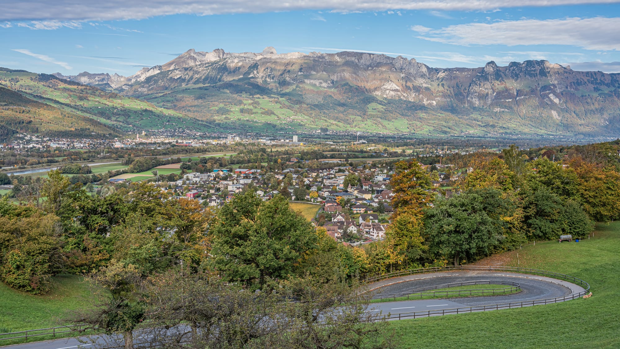 A view down over a small town in a green valley, from beside a castle