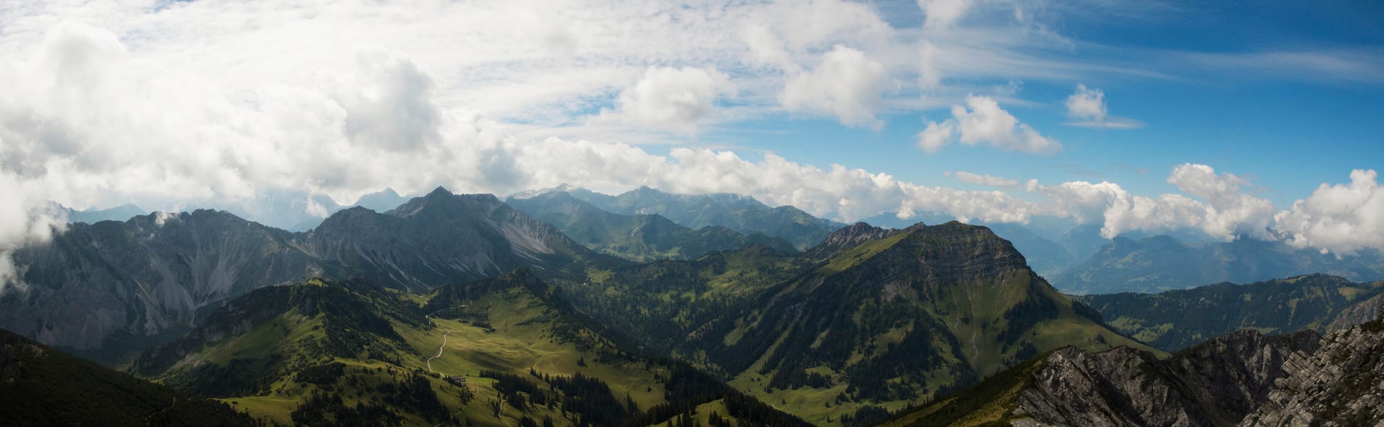 A hiking trail across high alpine grassland with jagged peaks all around