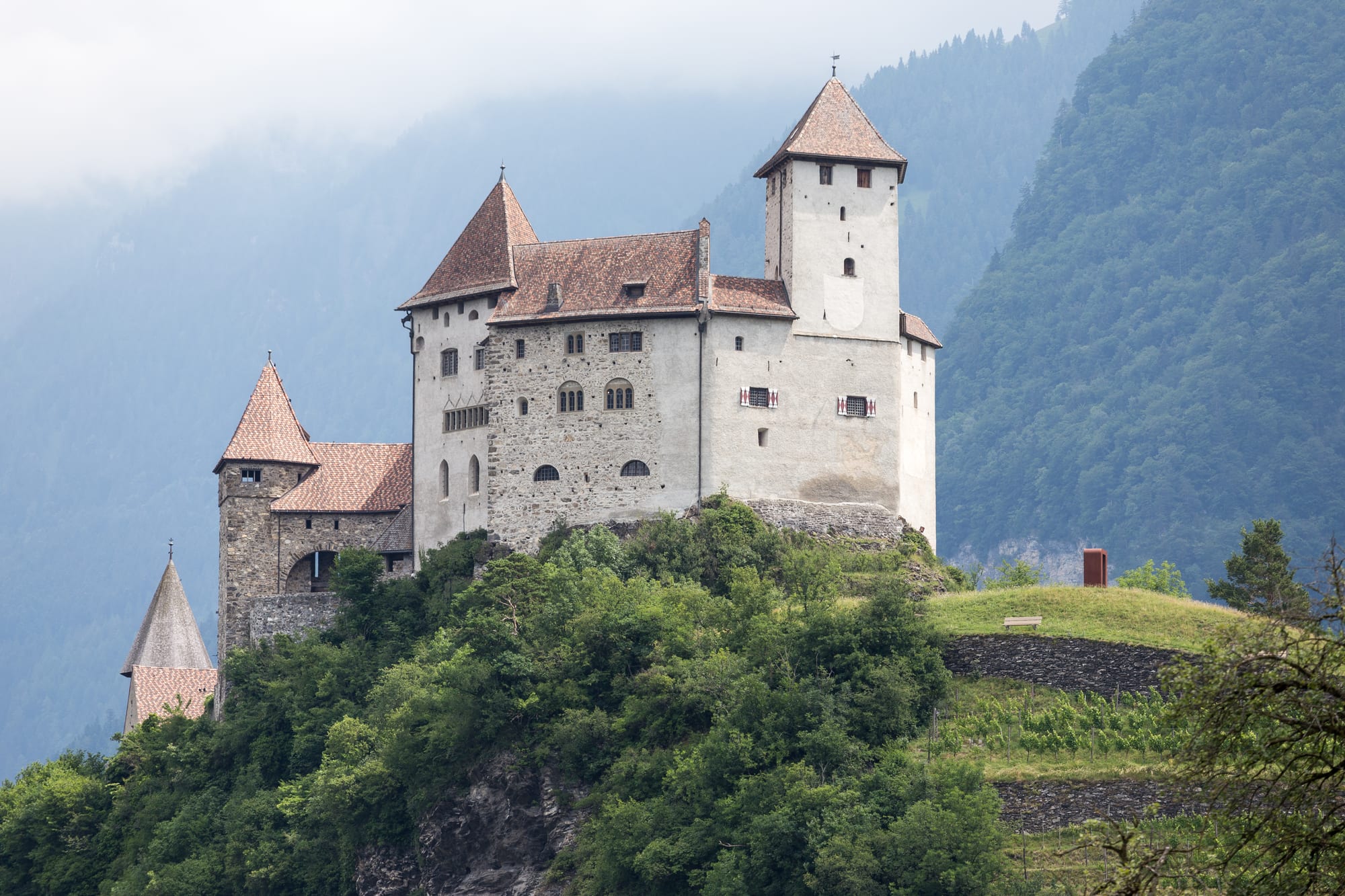 A hilltop medieval castle with a round tower above a small town