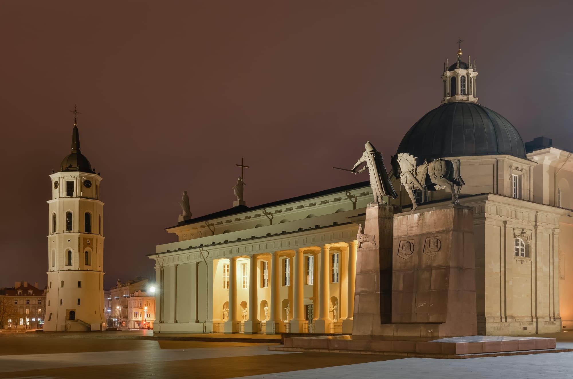 A white neoclassical cathedral with a freestanding bell tower on a large open square