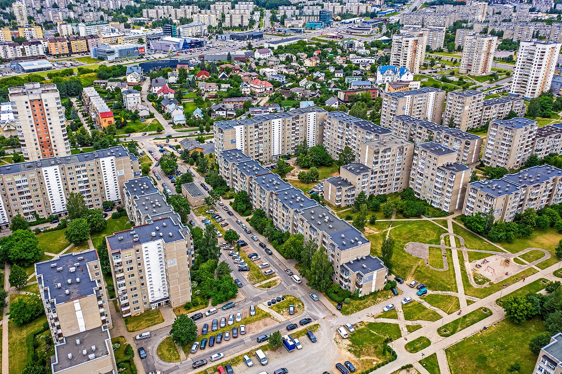 An aerial view of dense rows of Soviet-era apartment blocks in a Vilnius district, with smaller houses and green spaces between them