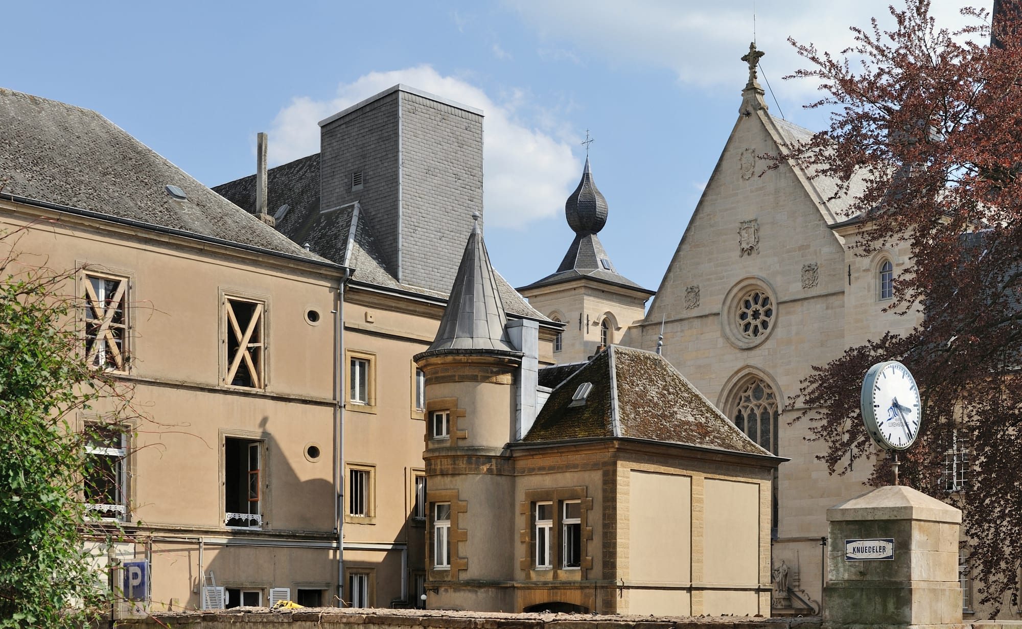 A dark stone late-Gothic cathedral with tall spires above a city square