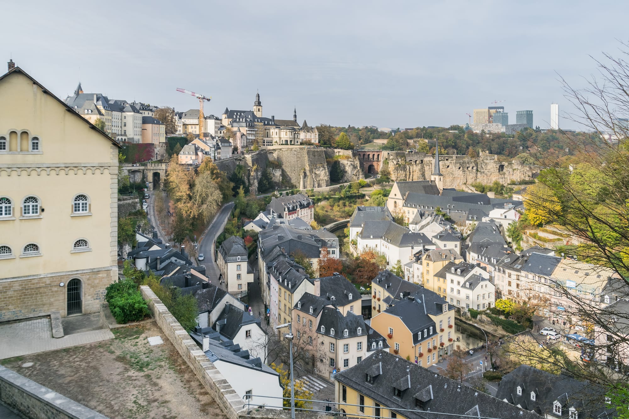 Old riverside houses and a church spire in a deep gorge below fortress walls