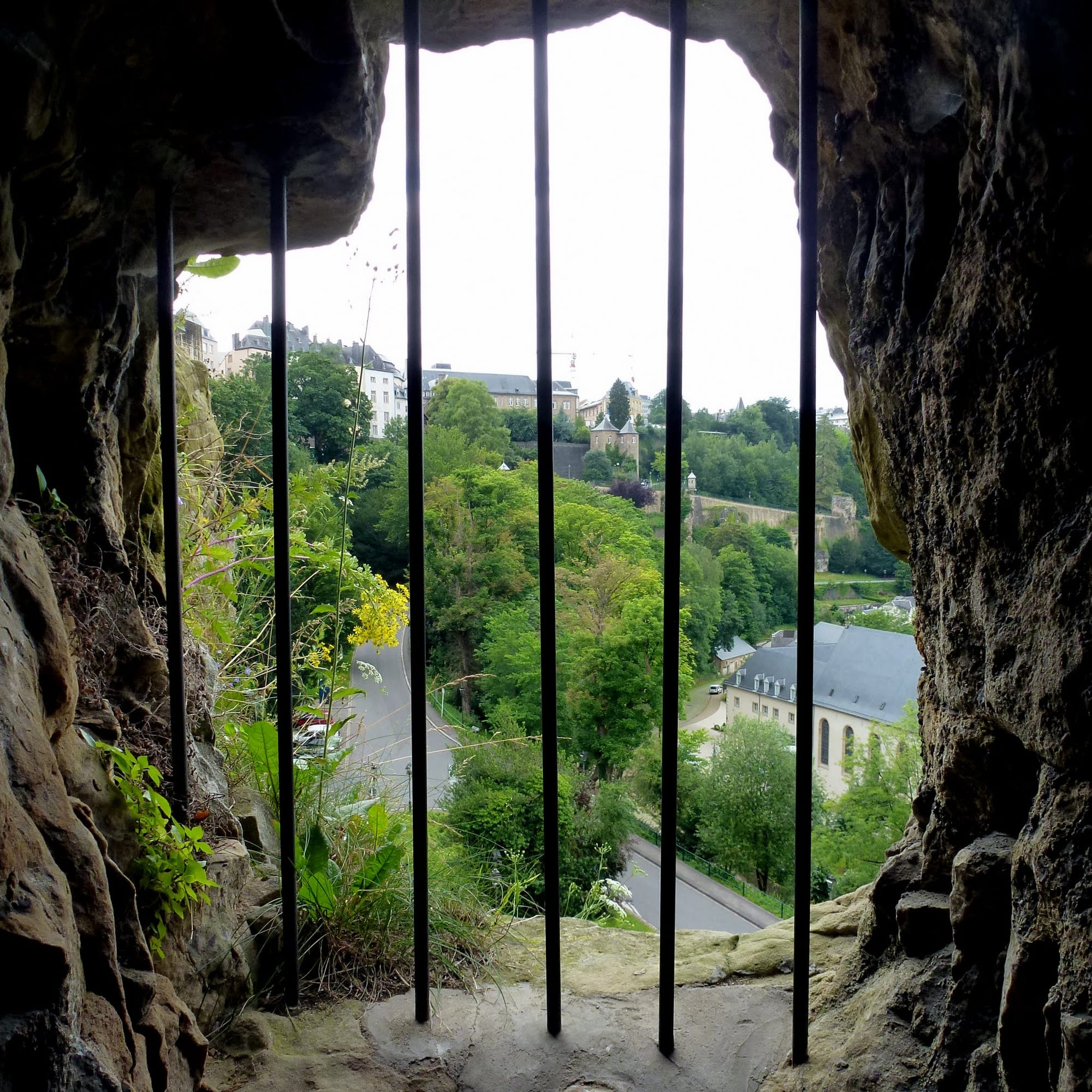 A dark stone tunnel gallery with openings looking out over a river valley