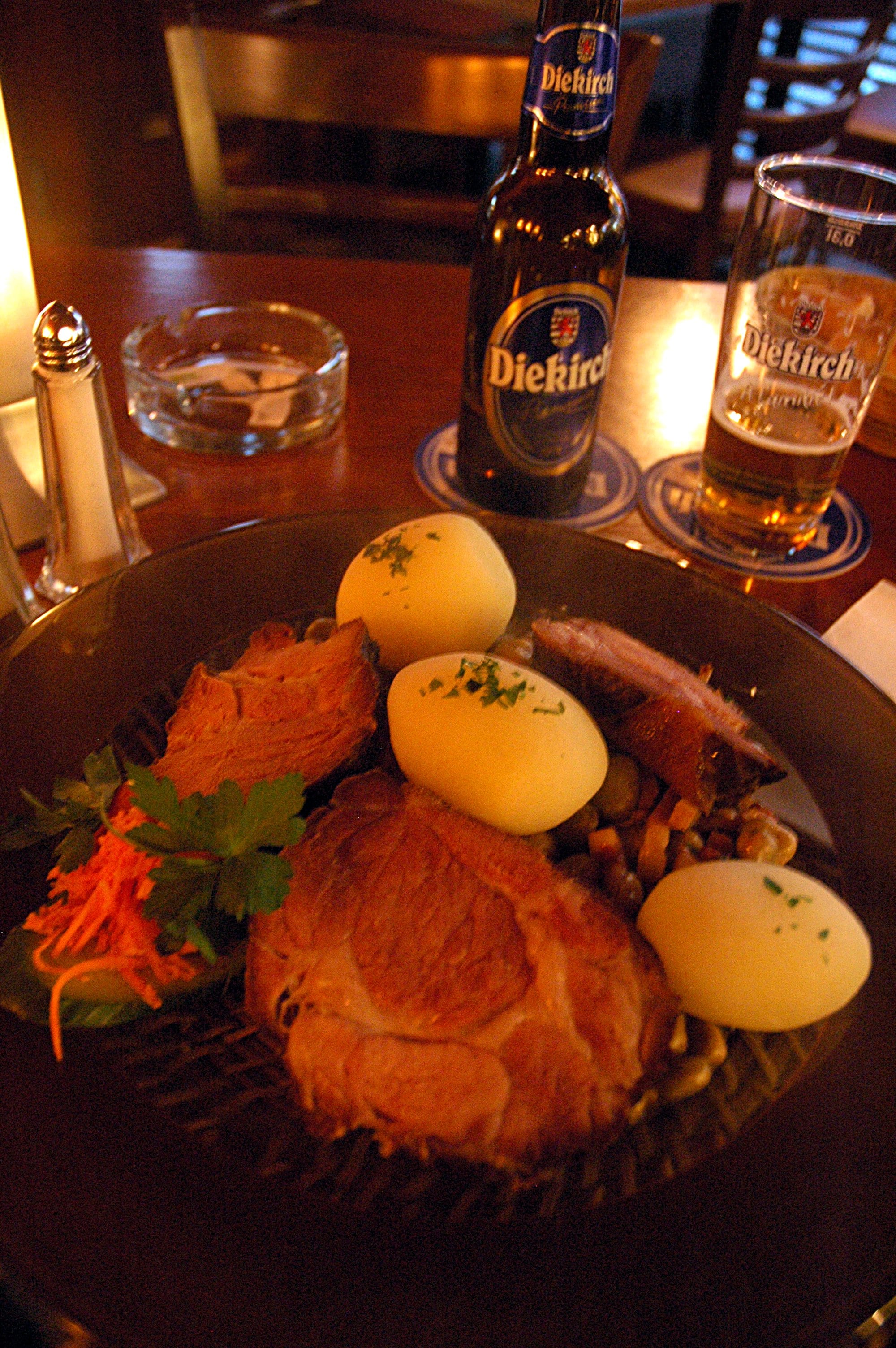 A plate of smoked meat with beans, served alongside a glass of beer