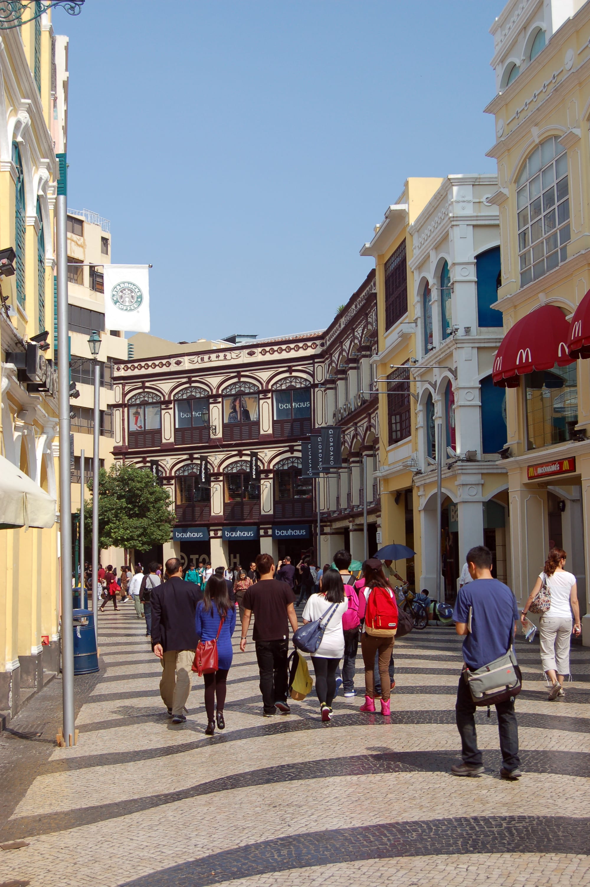 A wave-patterned paved square lined with pastel-coloured colonial buildings