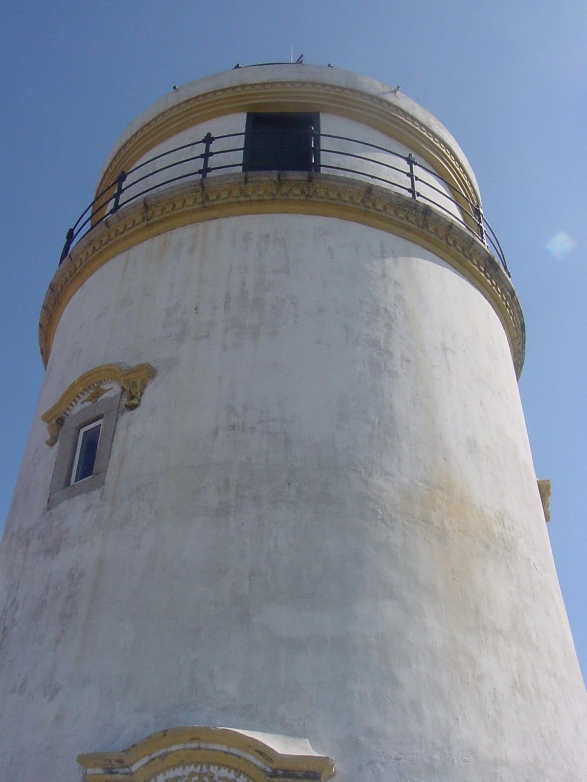 A white lighthouse and chapel on a hilltop above a city