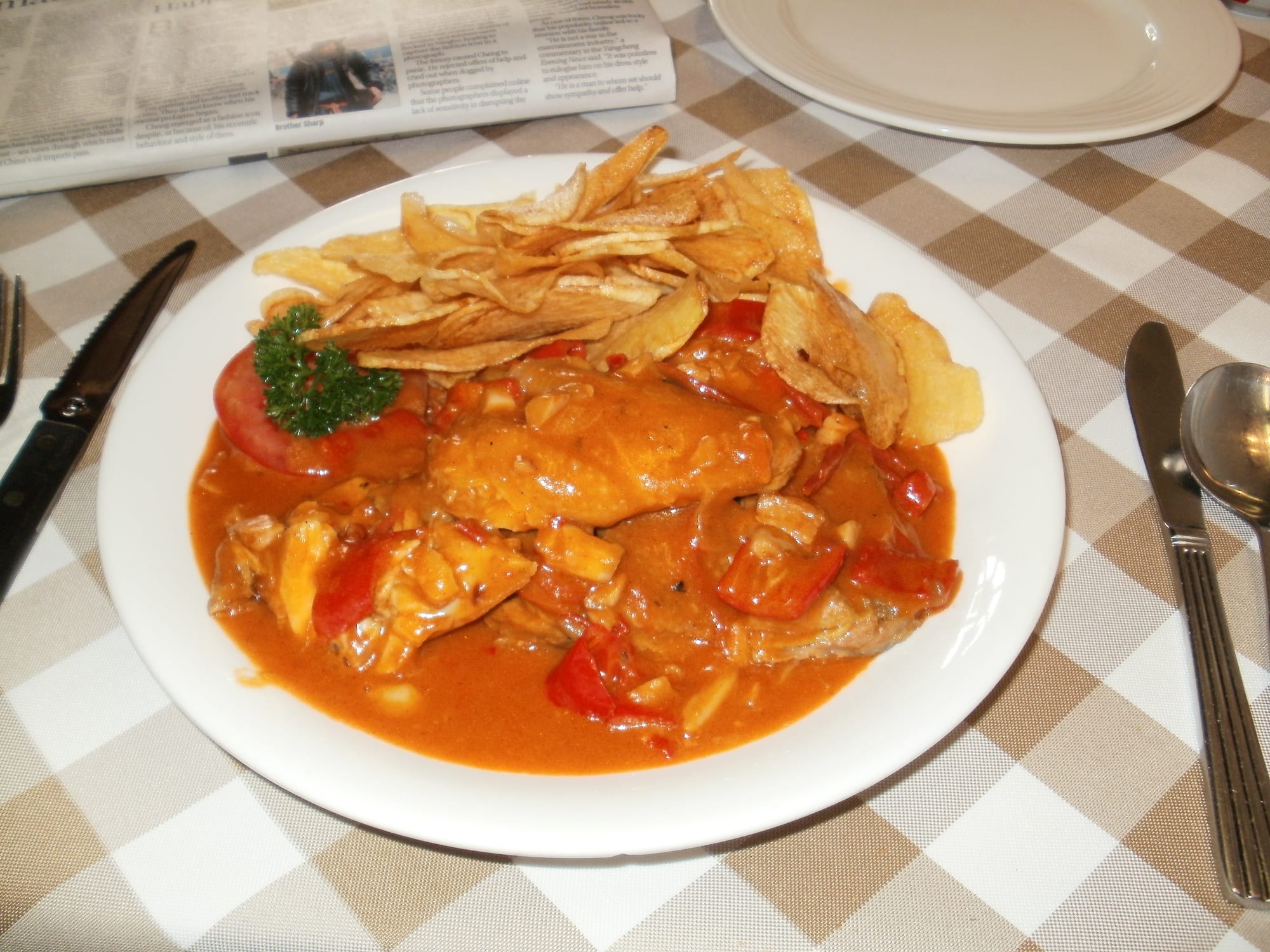 Roasted chicken pieces in a reddish spiced sauce, served with fries