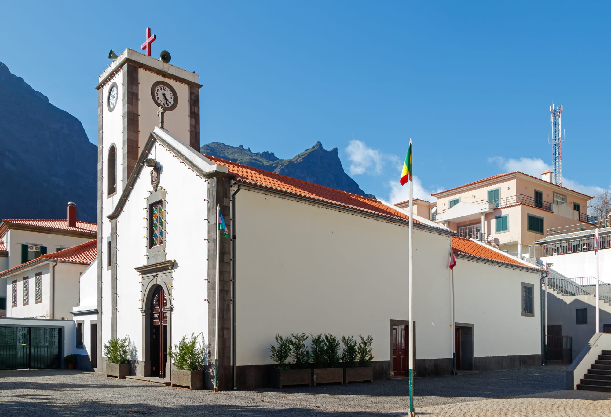A small white church in a village deep inside a green volcanic crater valley