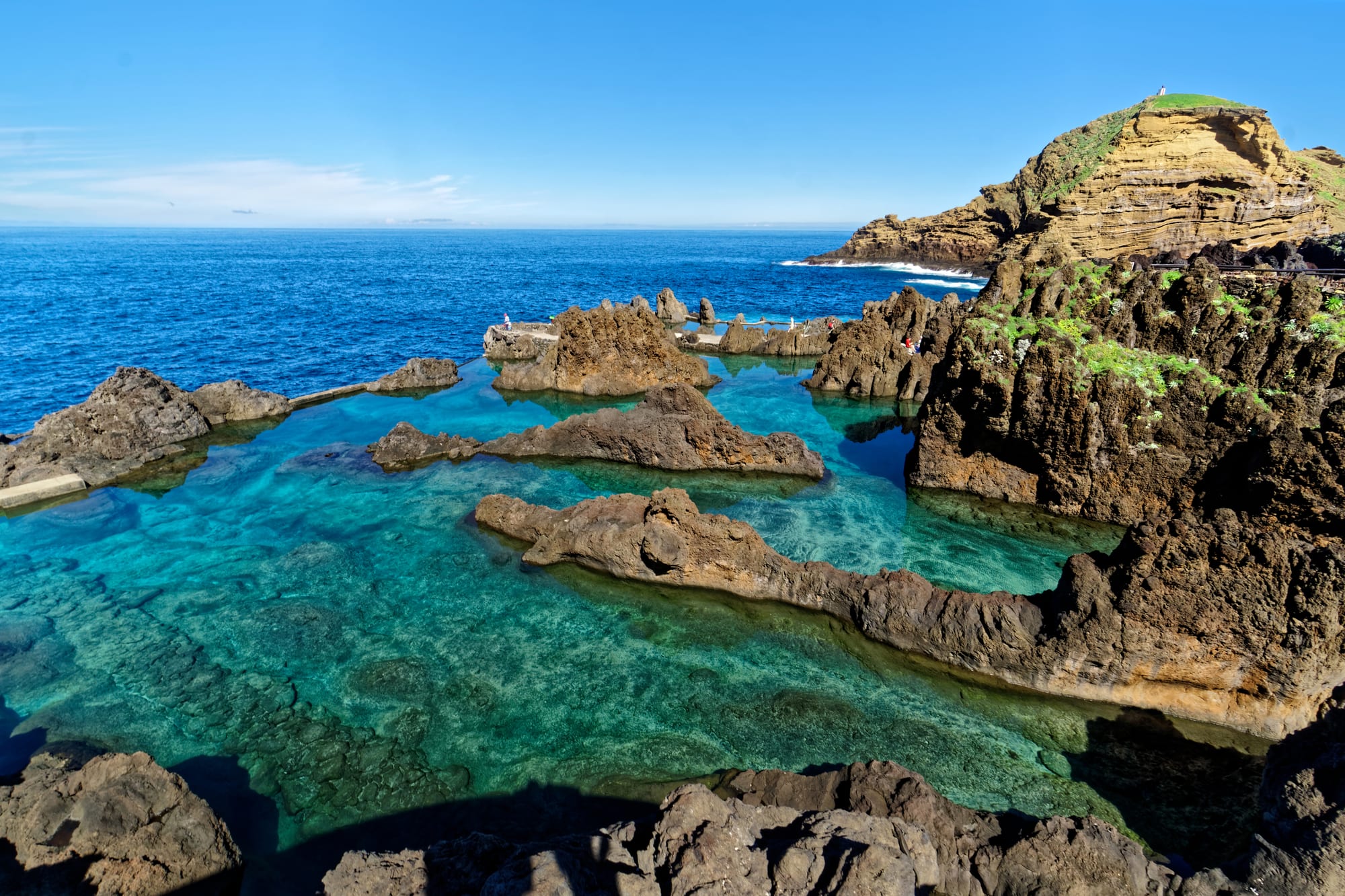 Natural swimming pools formed among black volcanic rocks by the sea