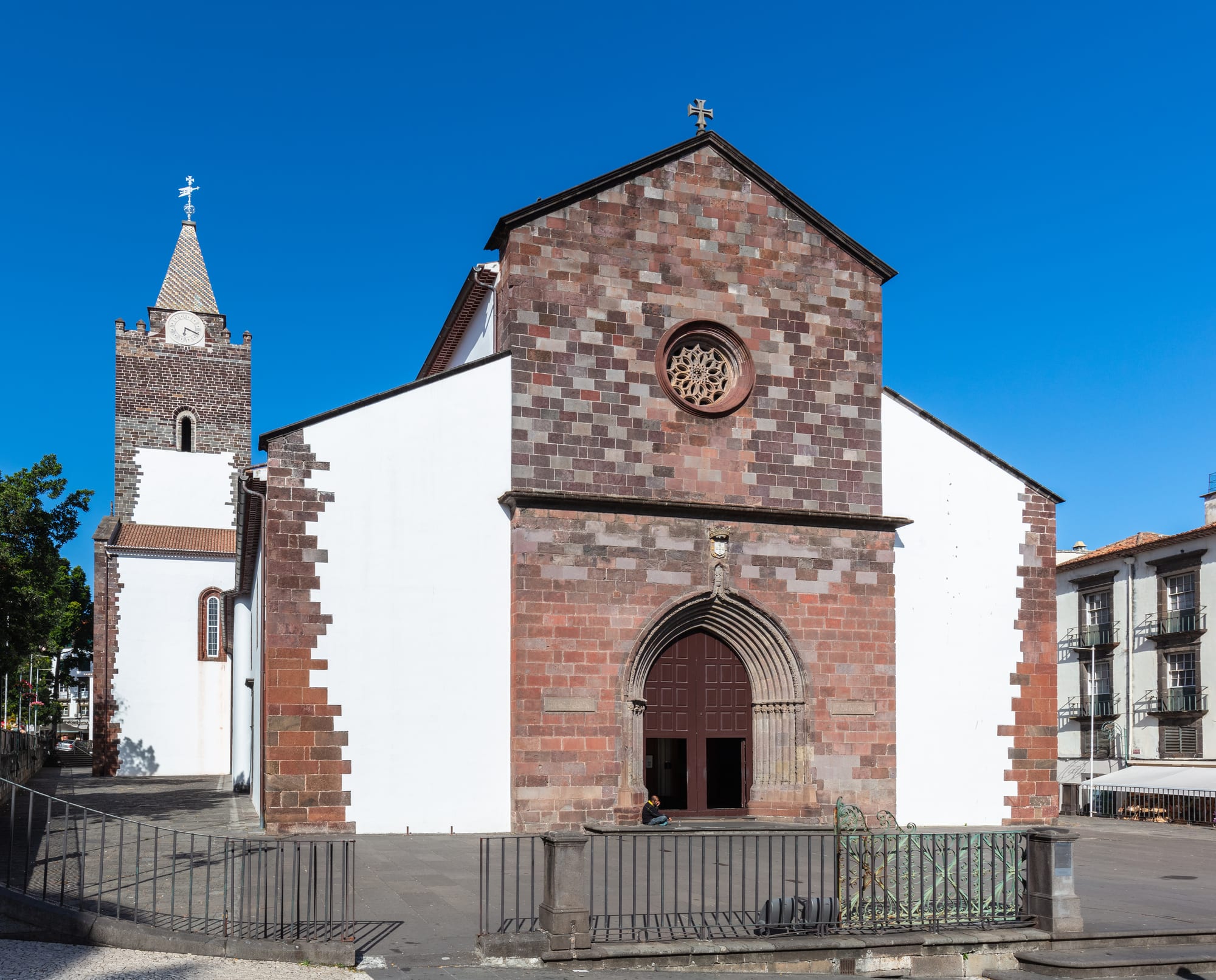 The white-and-stone Sé cathedral of Funchal with its dark tiled roof and bell tower