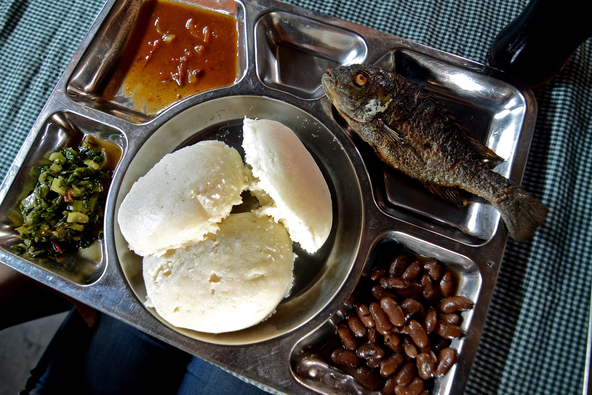 A plate of firm white maize porridge served with fried fish