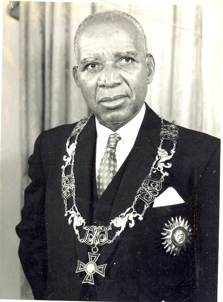 Hastings Banda in a three-piece suit and homburg hat, holding a fly whisk