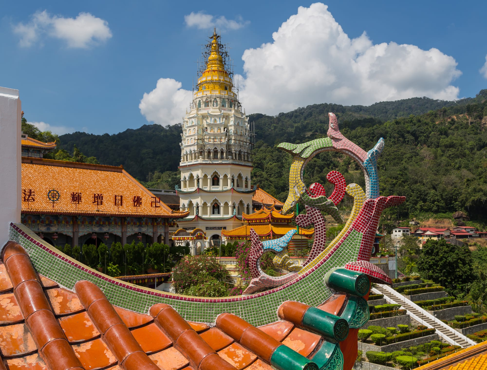 A tall multi-tiered Chinese-Thai-Burmese pagoda rising above temple rooftops on a hillside