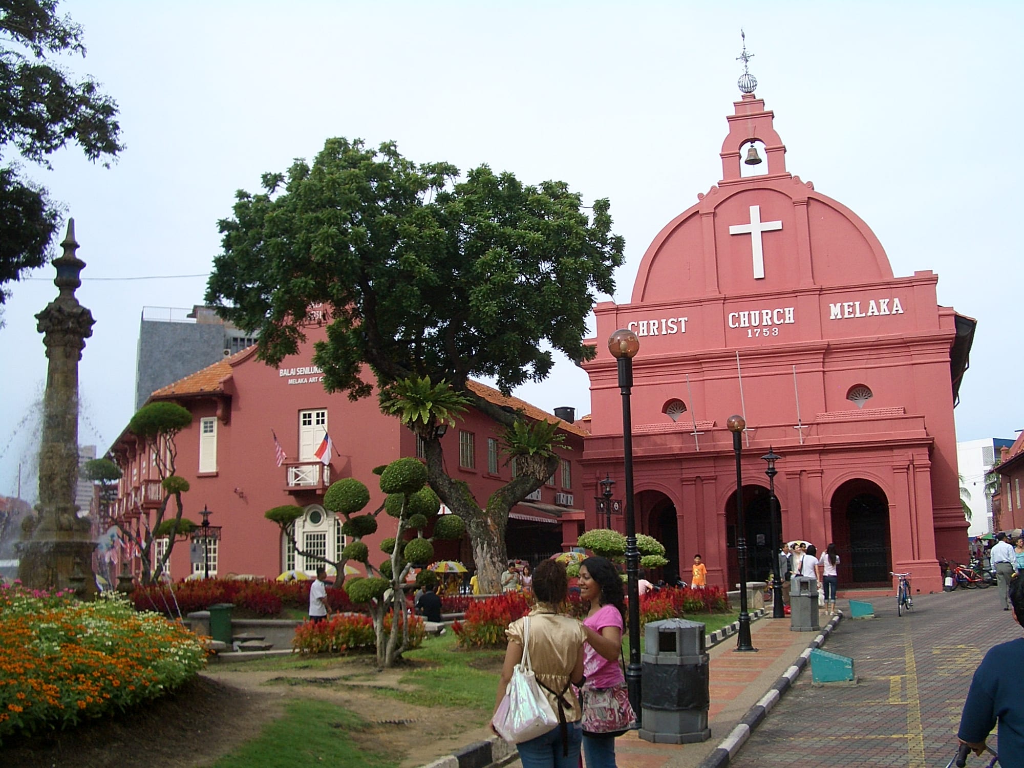 A salmon-red colonial church with a Dutch gabled facade on a town square