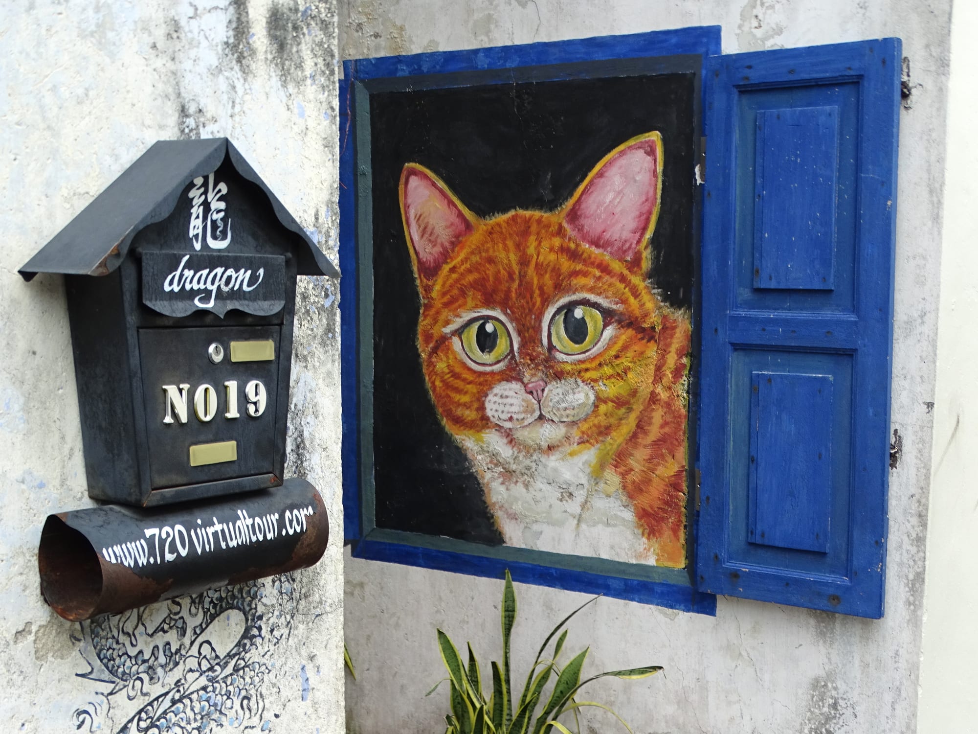 A wall mural of children on a bicycle beside an old shophouse street