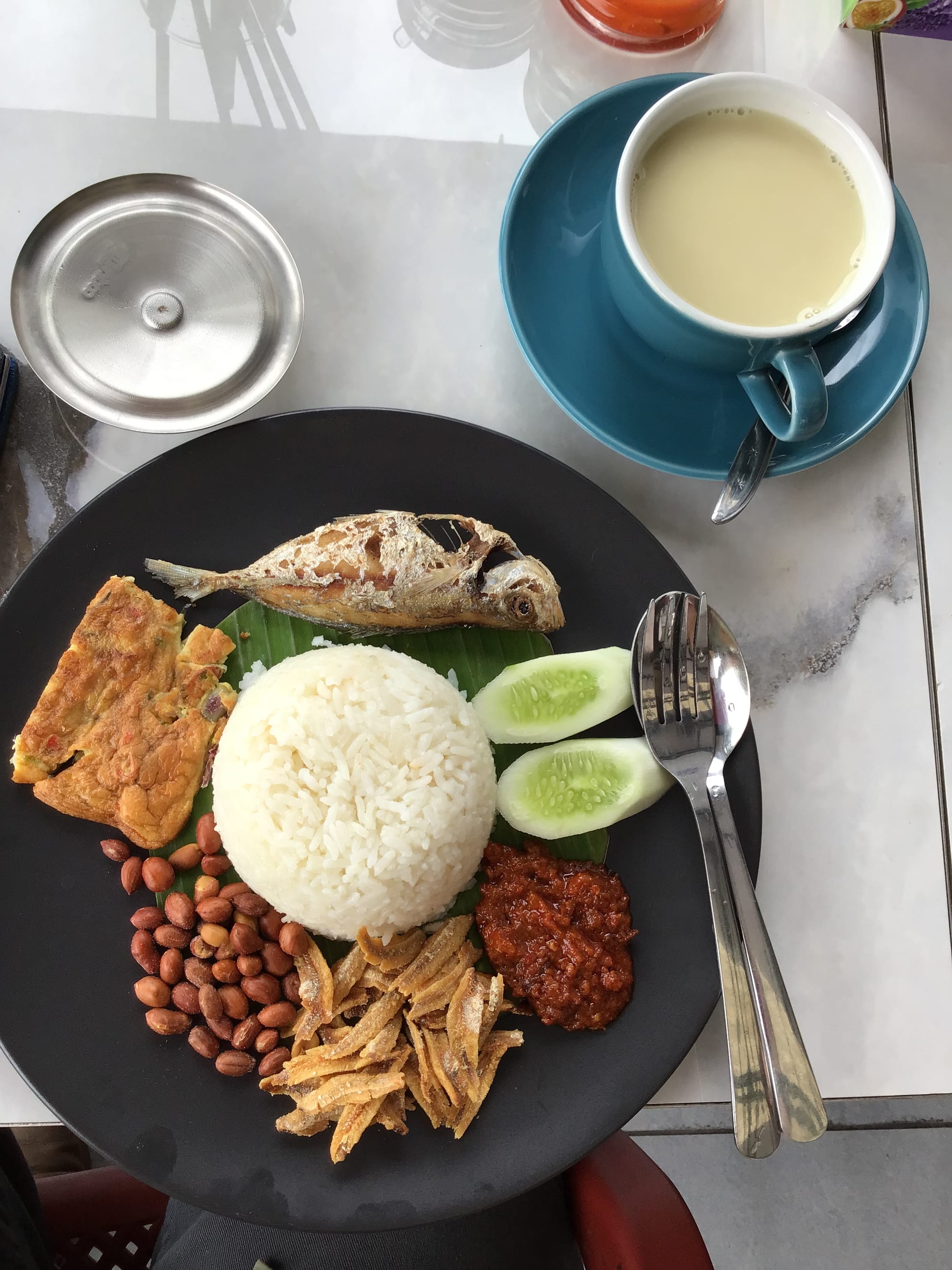 Coconut rice served with sambal, egg, peanuts and anchovies on a plate