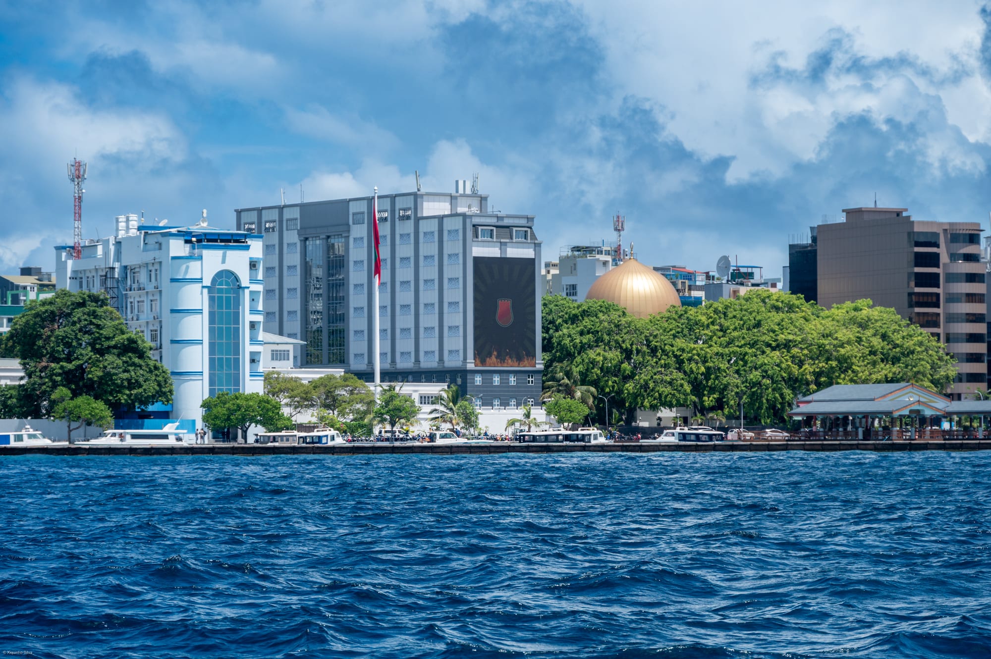 A tightly packed skyline of tall buildings crammed onto a small island, surrounded by sea