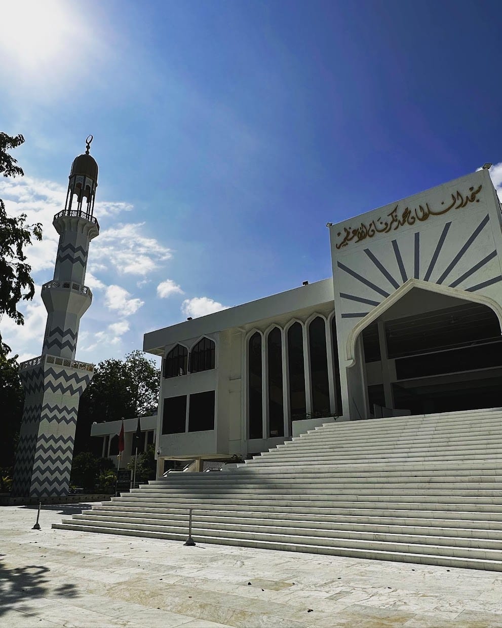 A large modern mosque in Malé with a gold dome and a tall minaret