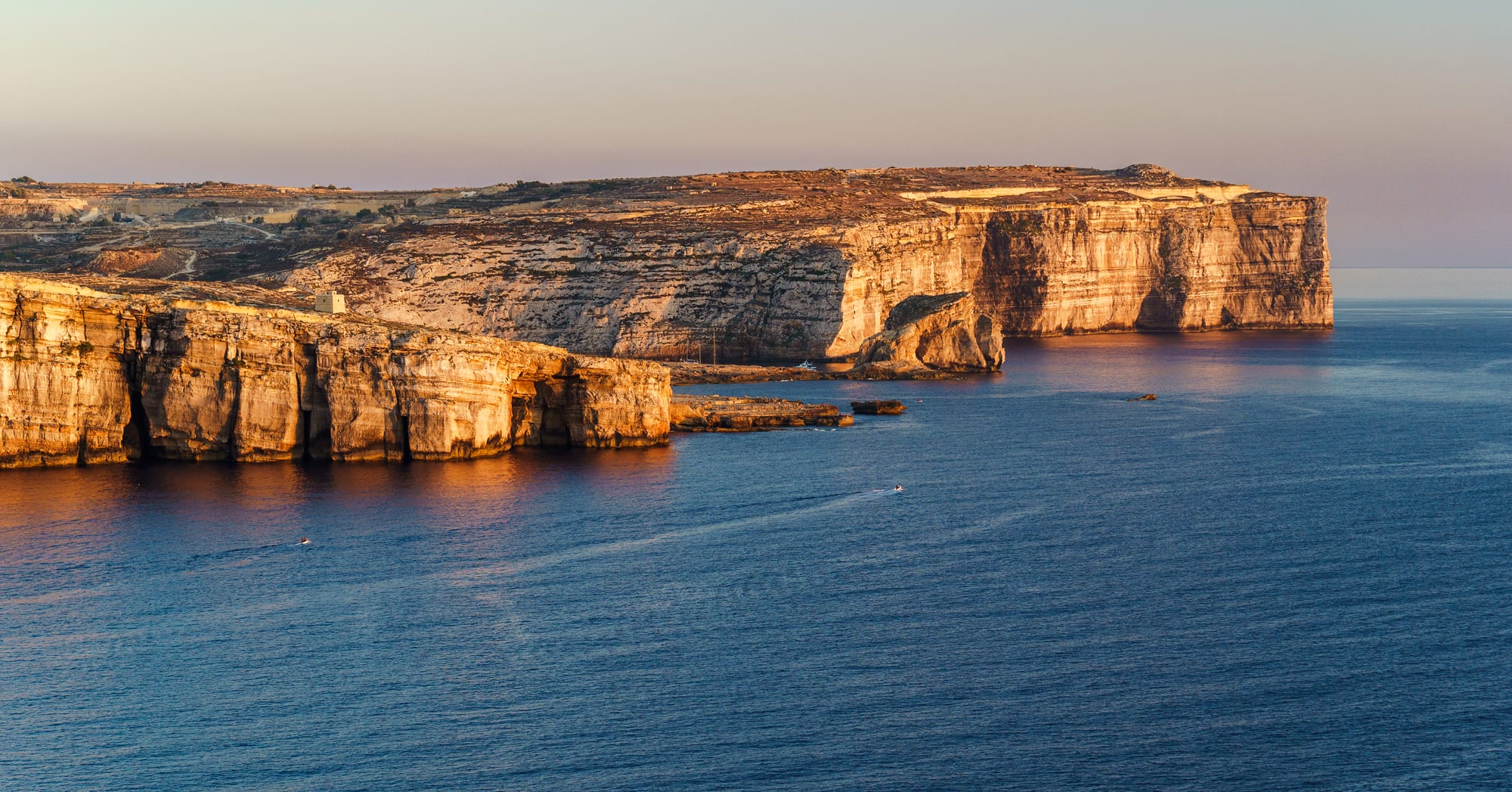 Golden limestone cliffs and rock formations along a rugged coastline