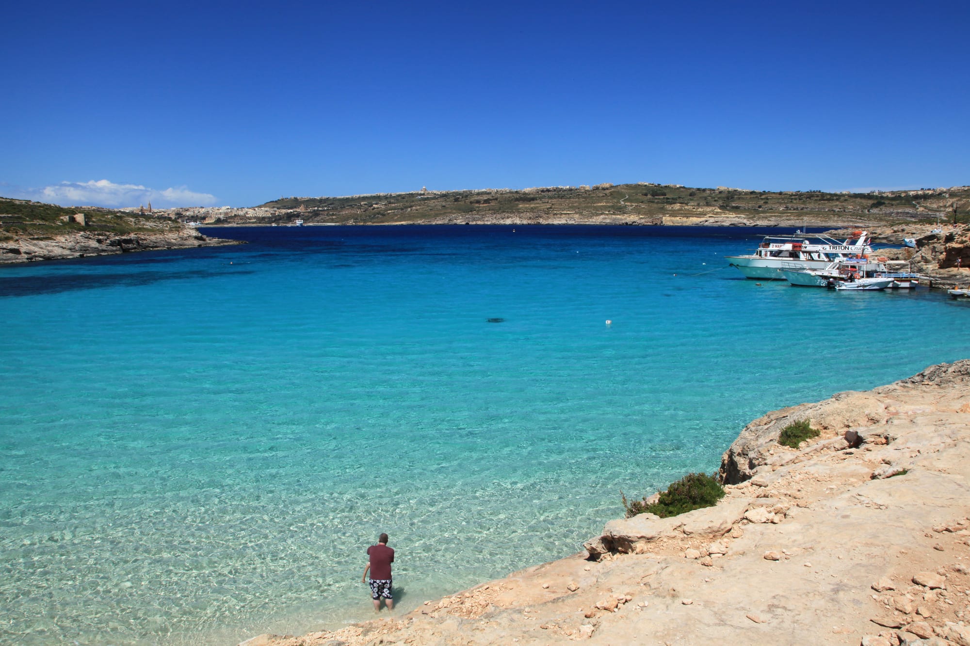 A swimmer wading into an extremely clear, bright turquoise shallow lagoon
