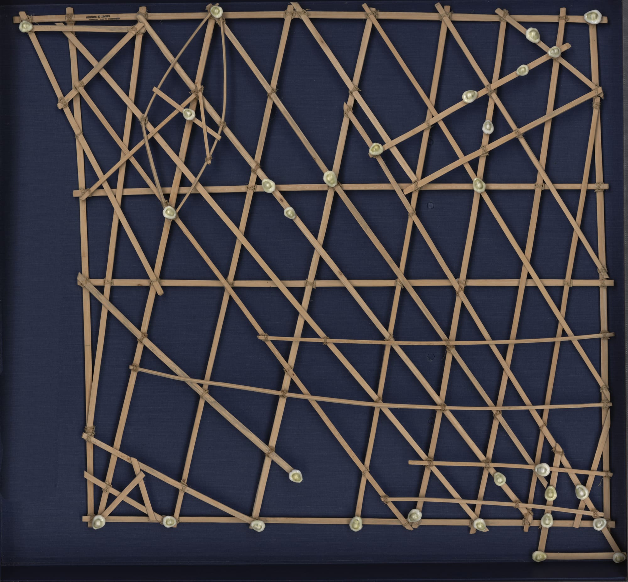 A lattice of coconut-frond sticks tied together with small shells at the intersections