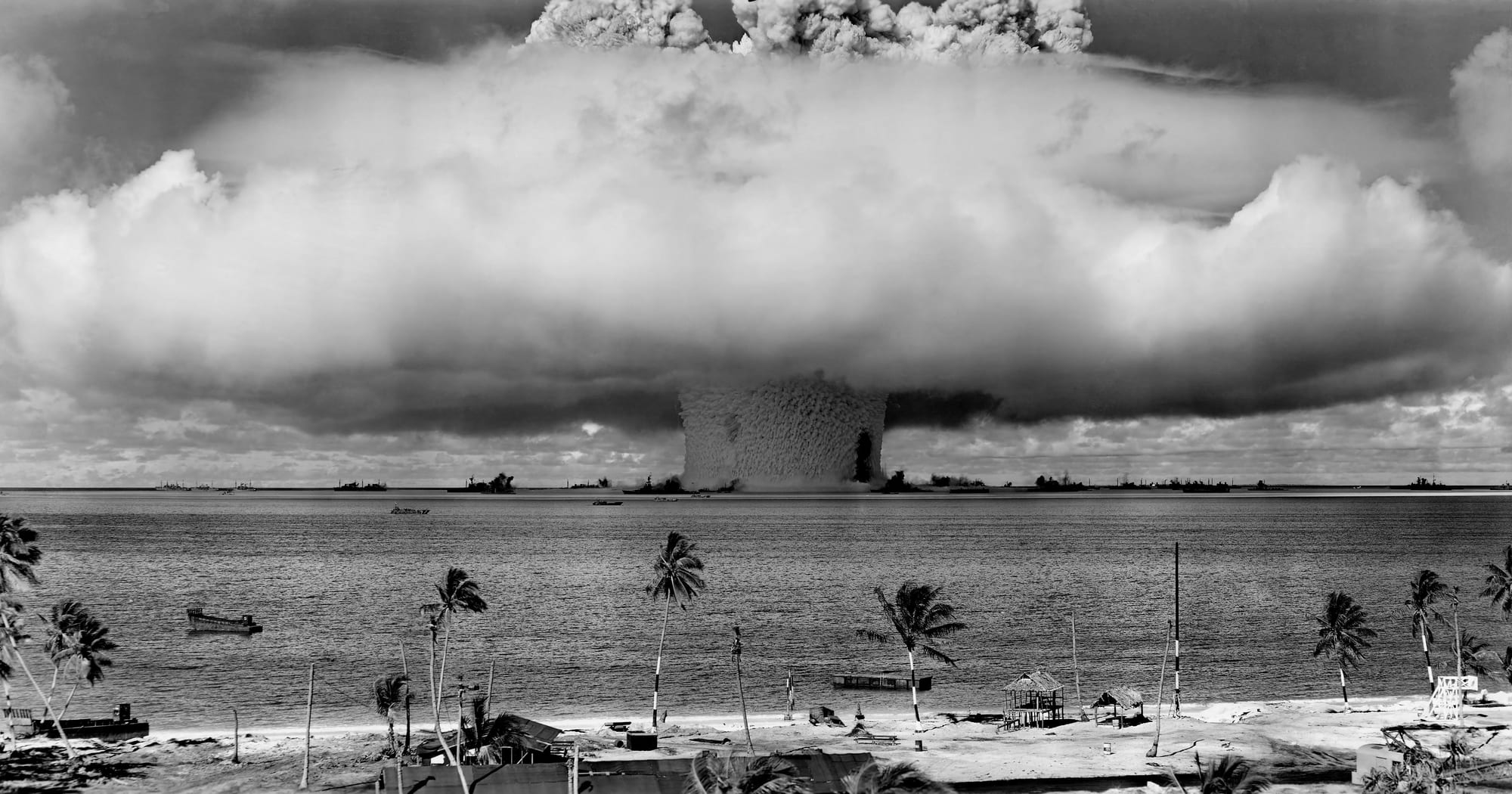 A vast column of water and spray rising from Bikini lagoon around warships during a 1946 nuclear test