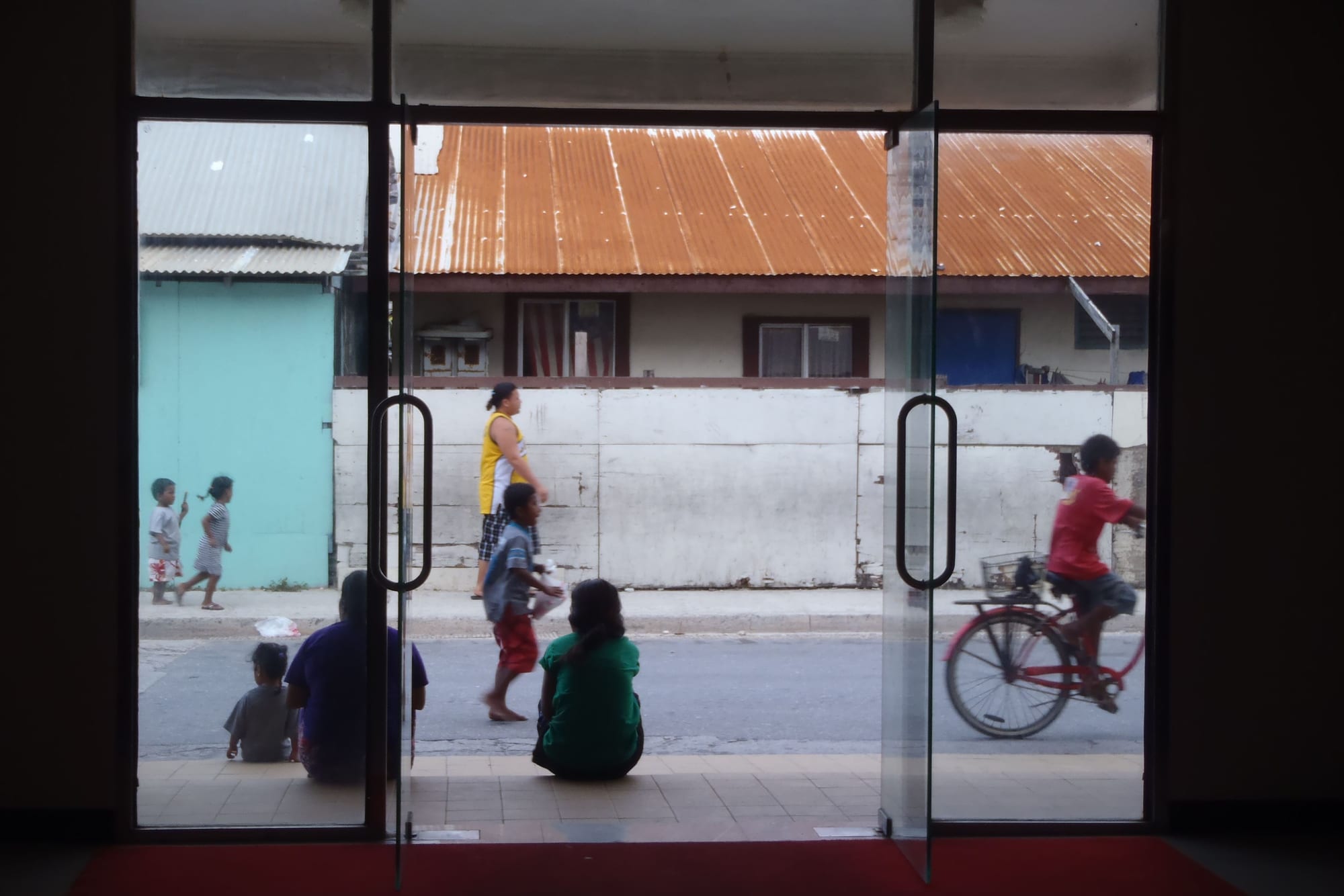 A crowded street of low concrete buildings and utility poles on the tiny island of Ebeye