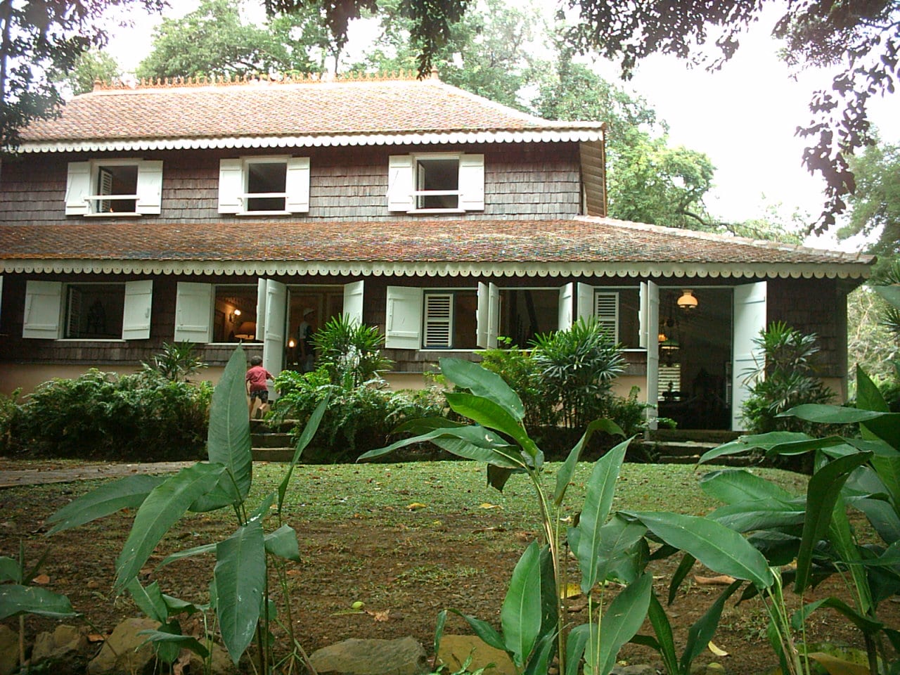 A restored white colonial plantation house surrounded by tropical gardens