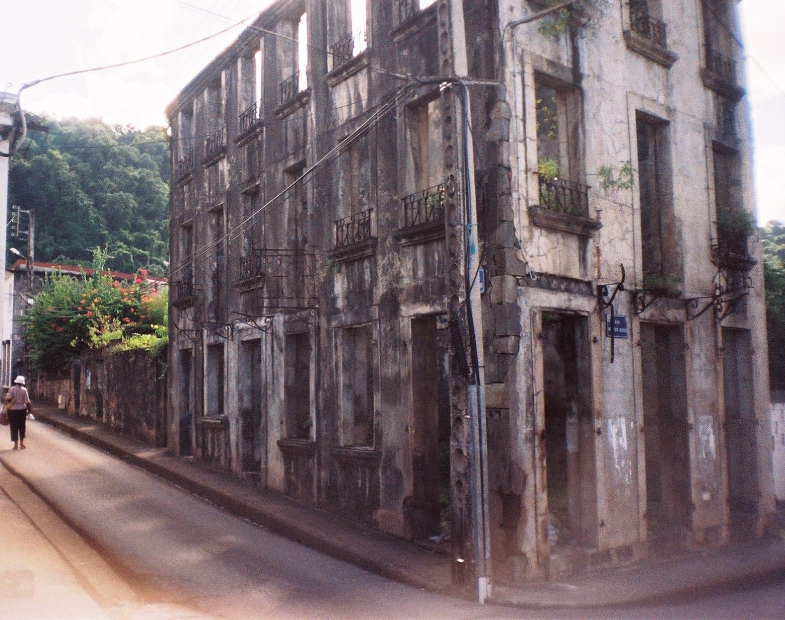 Ruined stone walls of an old theatre standing among modern buildings, a volcano visible behind