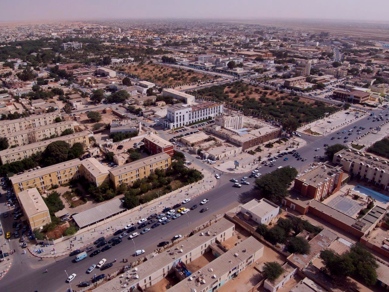 A wide dusty street in a low-rise desert capital city