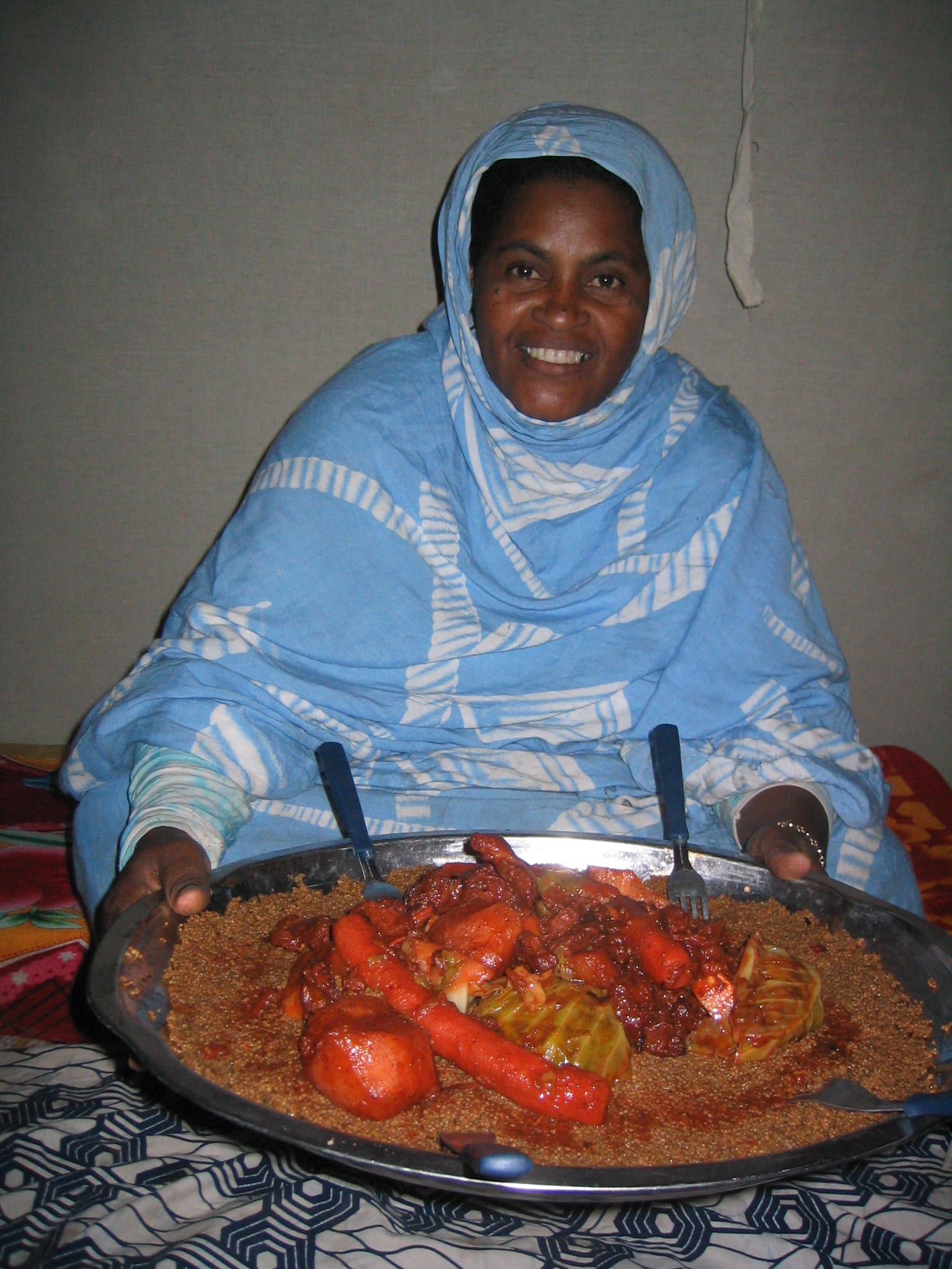 A large platter of couscous topped with meat, prepared inside a tent