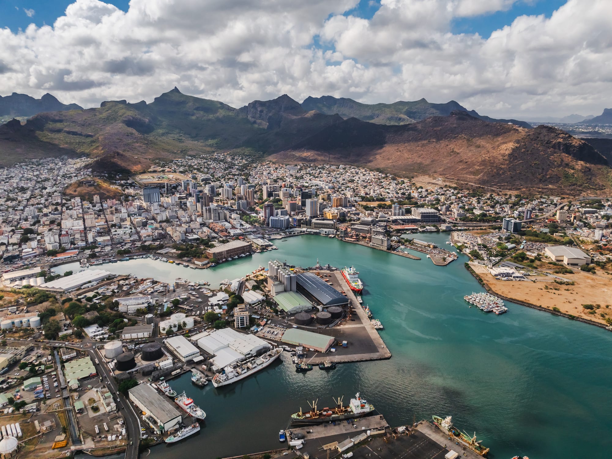 A harbour city with modern buildings and mountains rising sharply behind