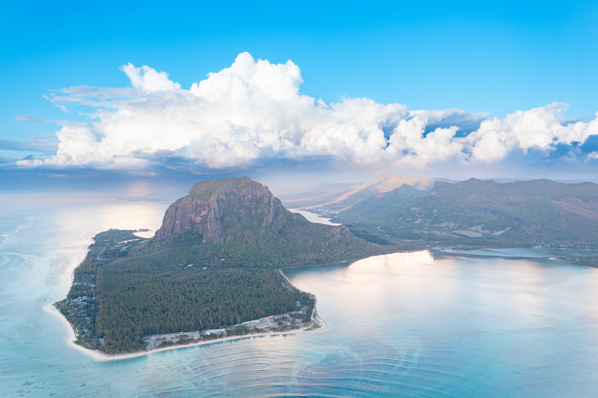 An aerial view of a dramatic mountain peninsula surrounded by turquoise lagoon and reef