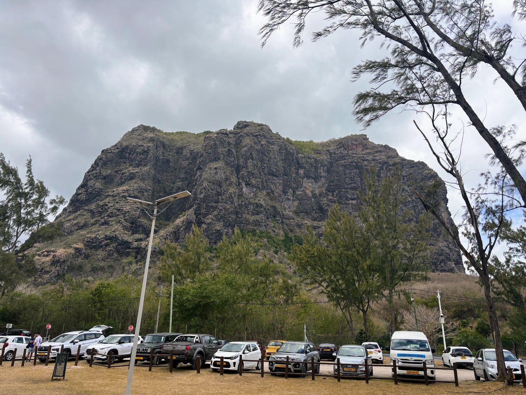 A steep, dark basalt mountain rising above a turquoise lagoon and white beach
