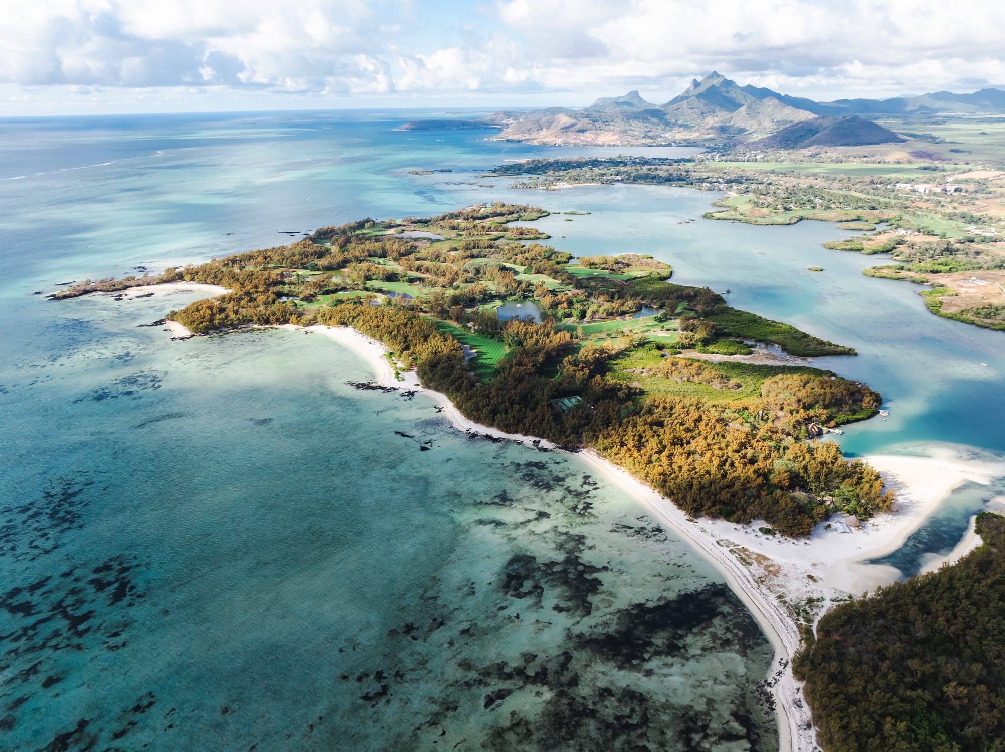 A palm-lined white sand beach curving around a turquoise lagoon on a small island