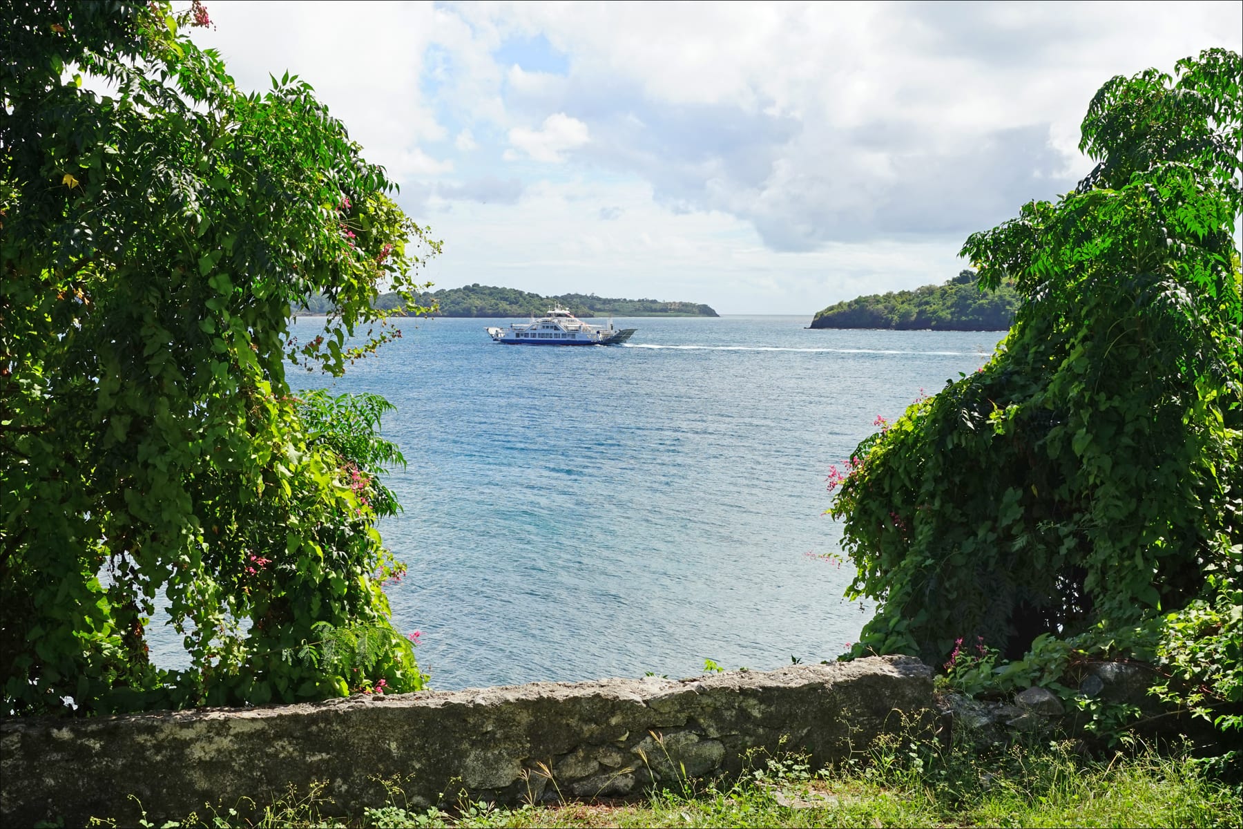 A ferry crossing a lagoon between two green islands