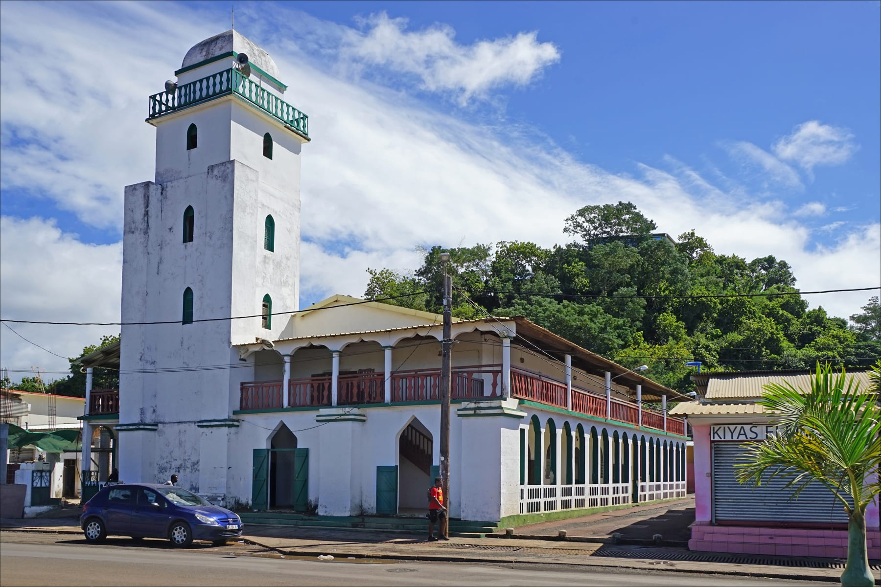 A white-and-green mosque with a slender minaret in a Mayotte town
