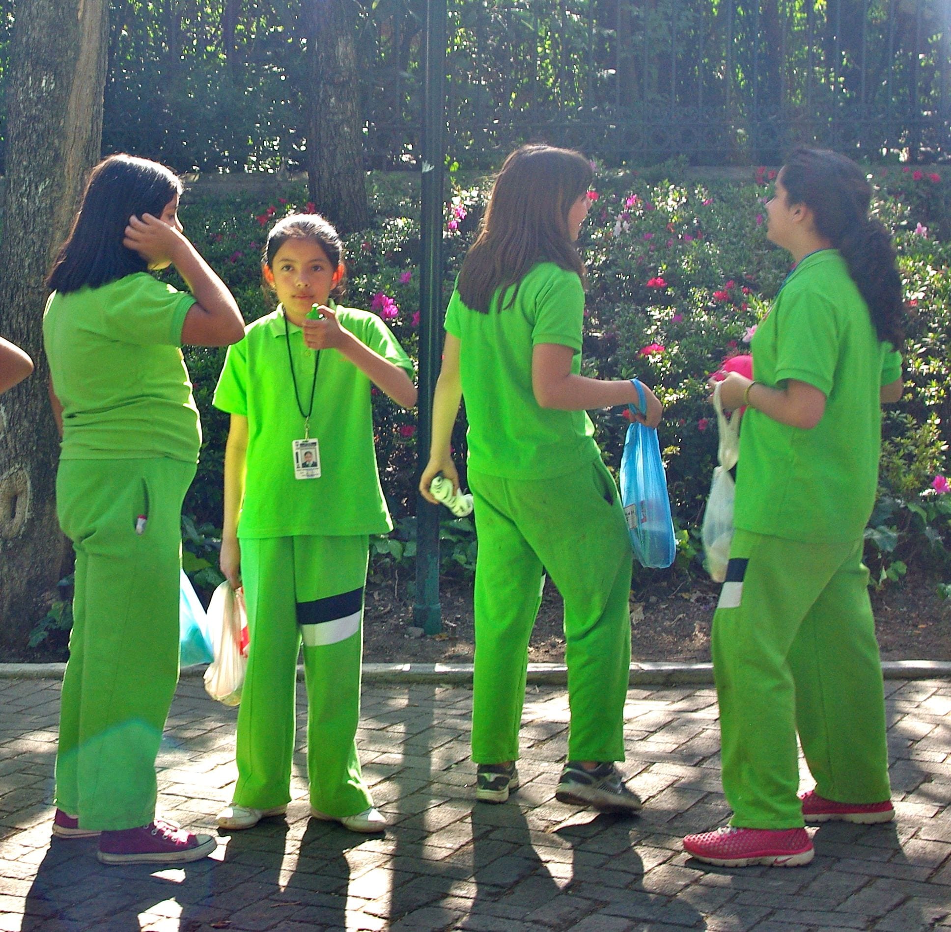 A group of schoolchildren in matching green uniforms standing together in a park