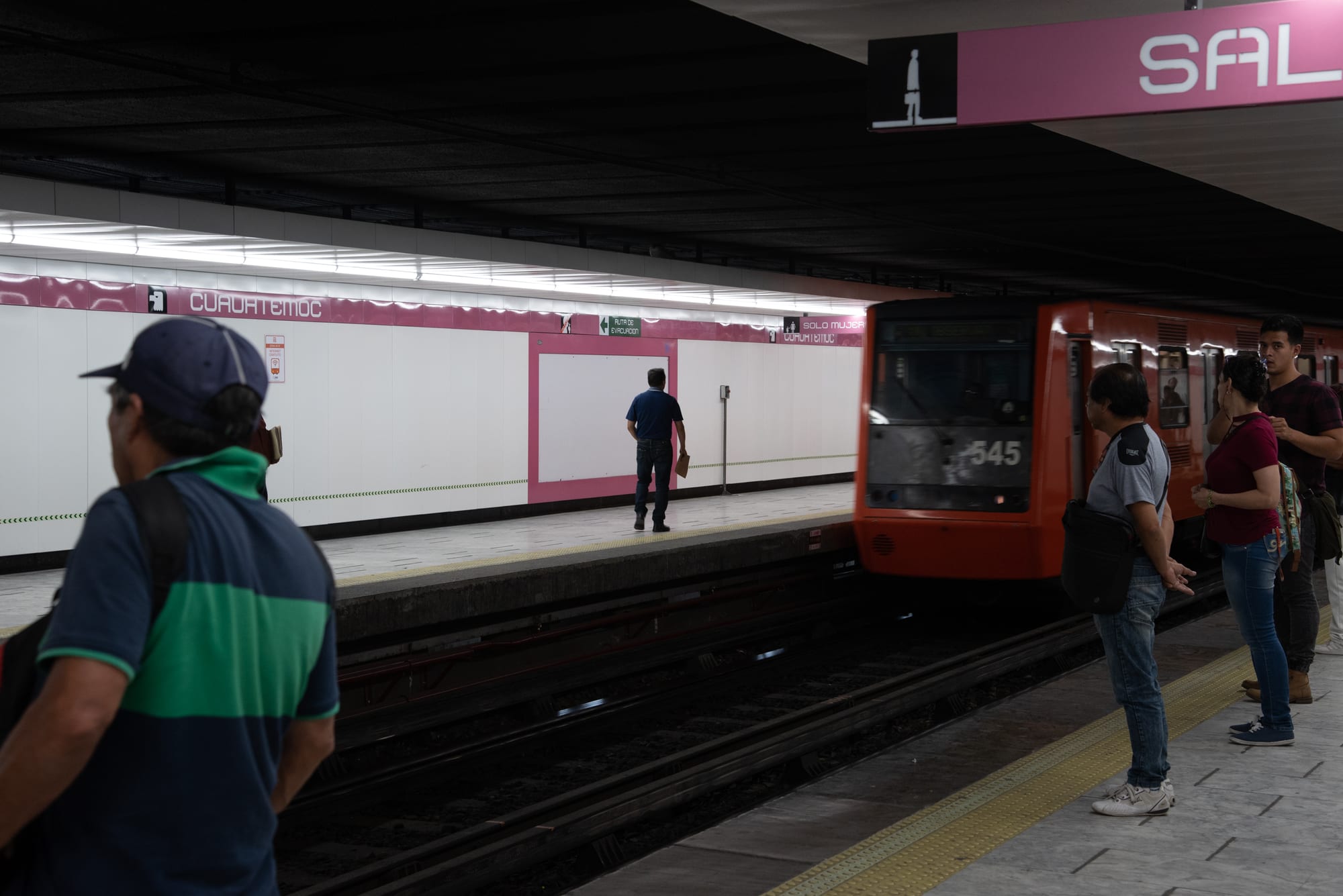 Commuters waiting on a Mexico City metro platform as a train arrives