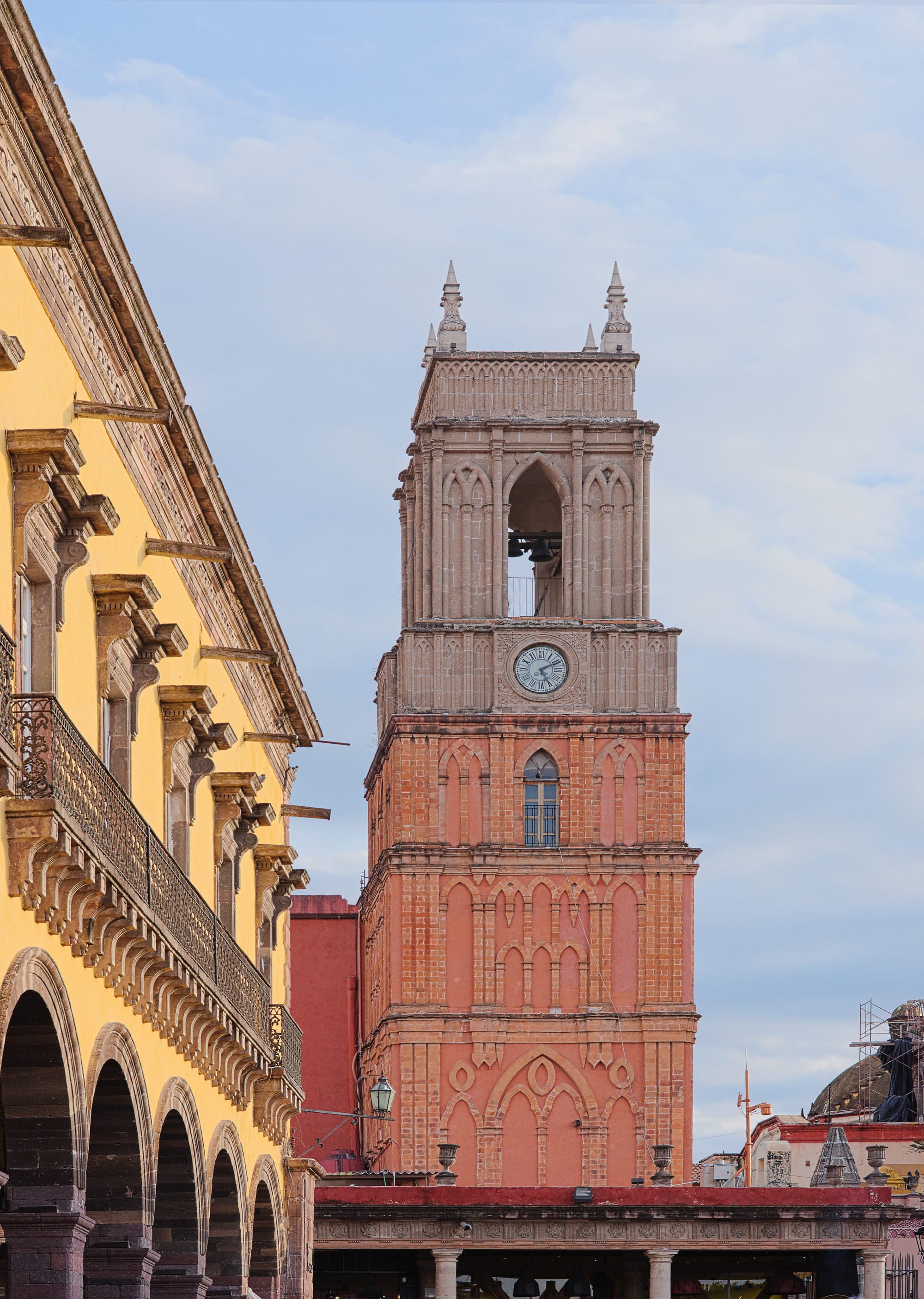 A pink neo-Gothic church tower rising above a colonial plaza
