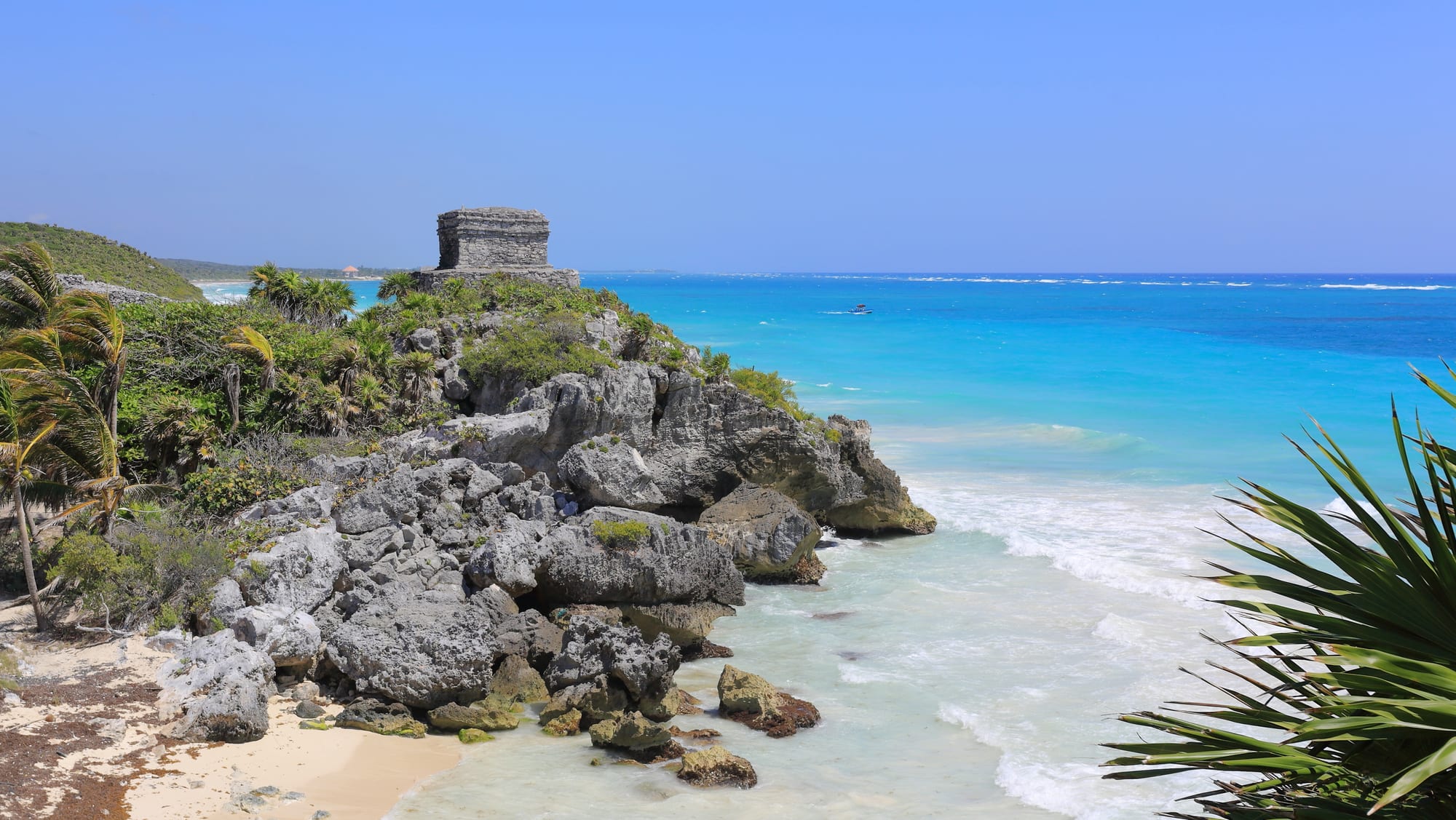 Small stone Maya ruins on a clifftop above a turquoise Caribbean beach