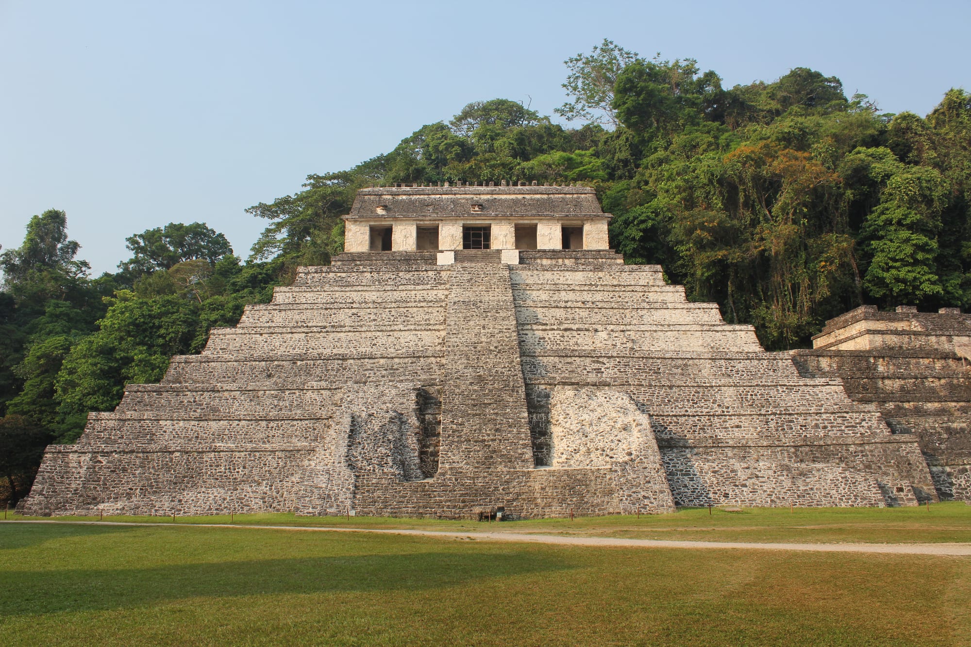 A stone Maya temple pyramid rising out of dense jungle