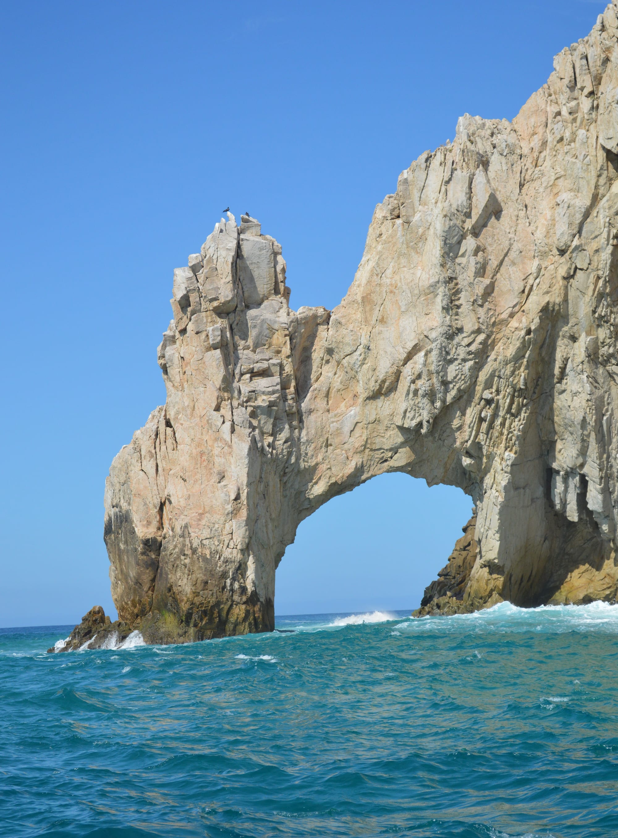 A rock arch formation where a rocky point meets the sea