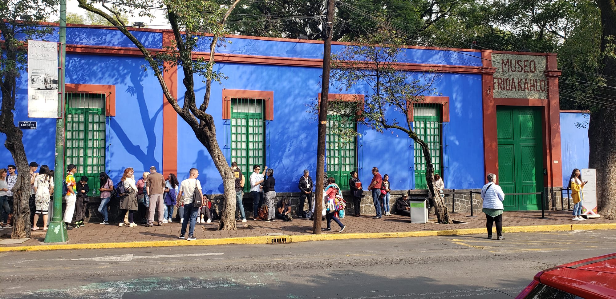 A cobalt-blue colonial street facade with green-shuttered windows and doors