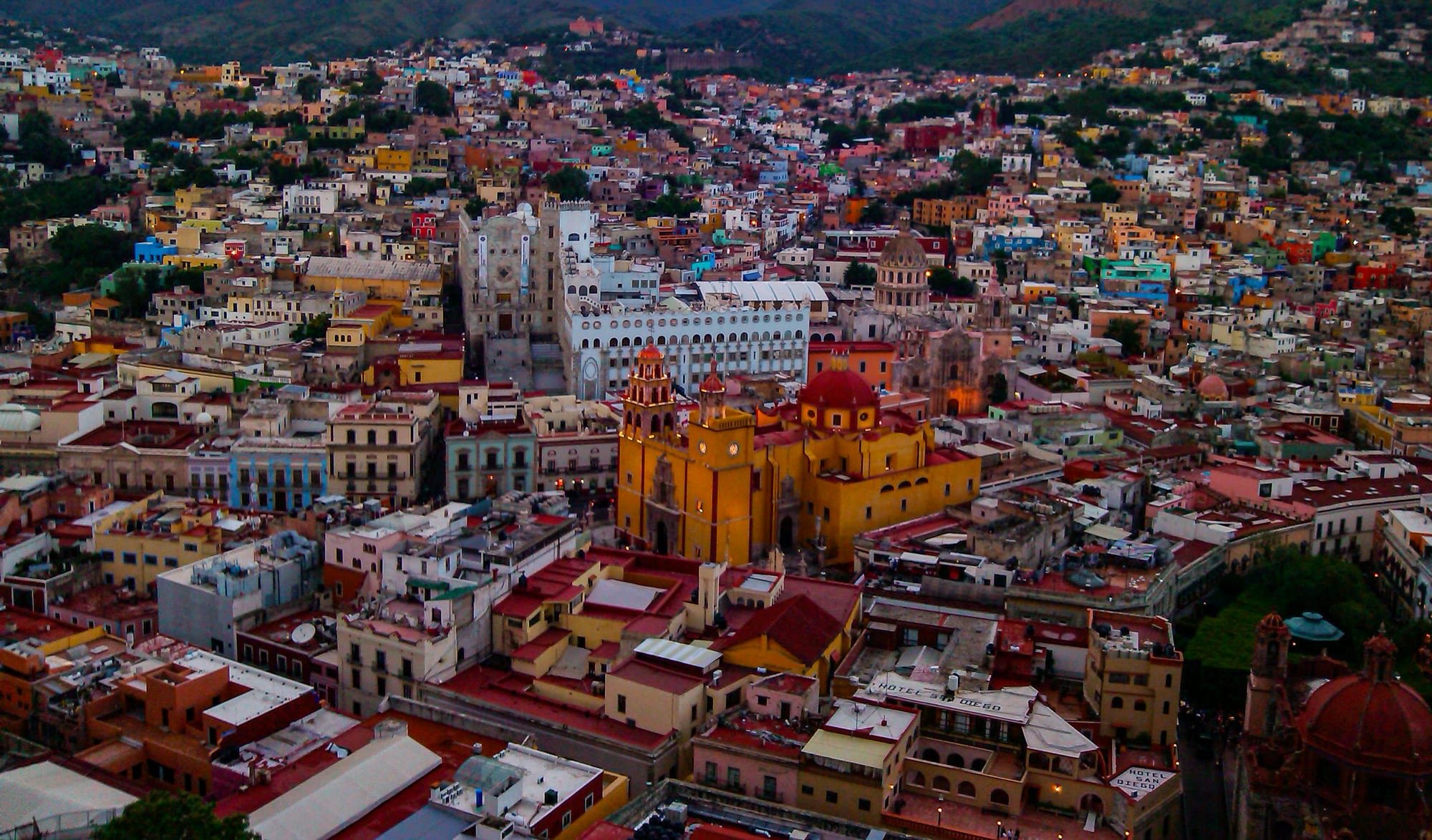 A hillside city of densely packed, brightly coloured houses and church domes at sunset